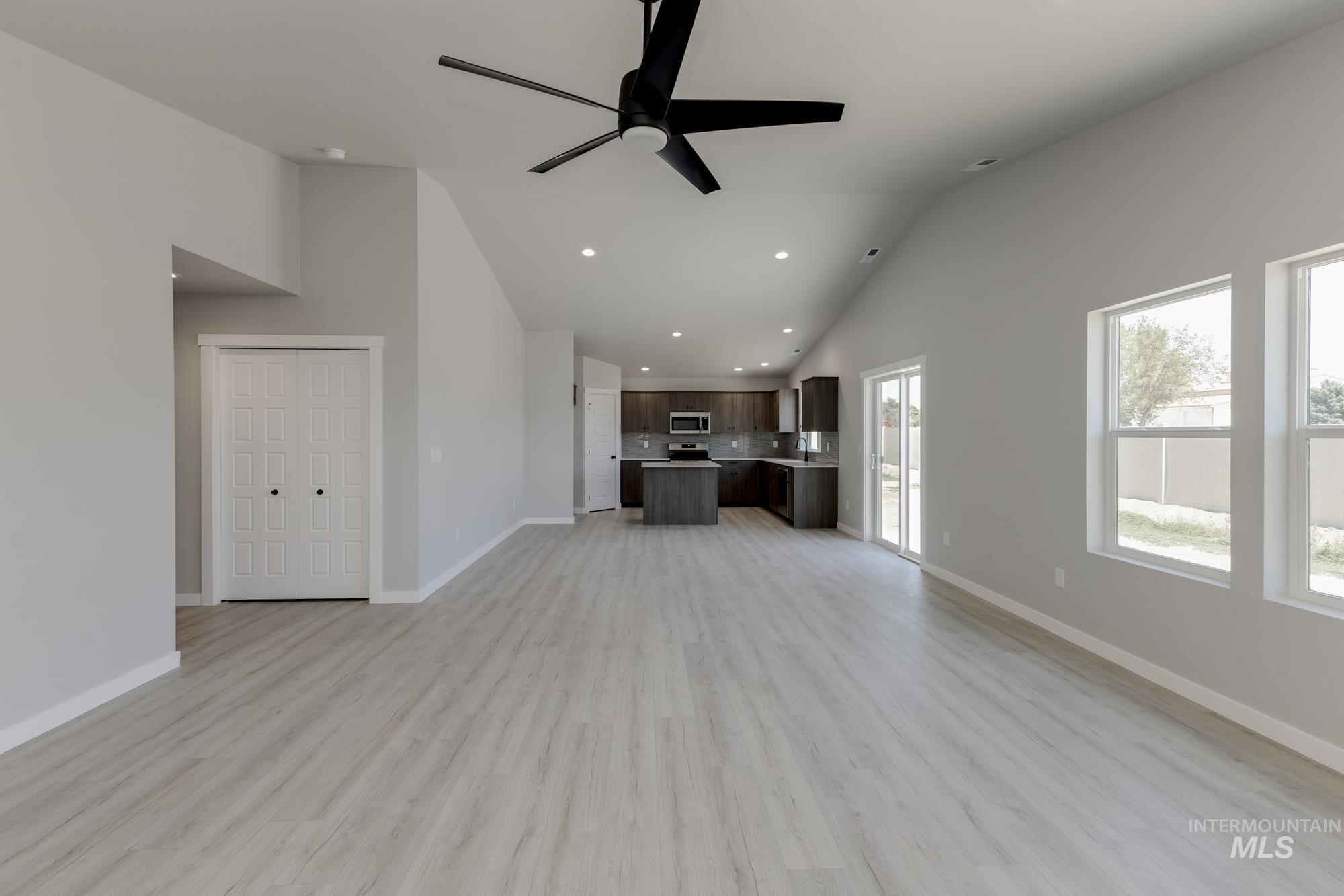 Unfurnished living room with recessed lighting, light wood-type flooring, a ceiling fan, and high vaulted ceiling