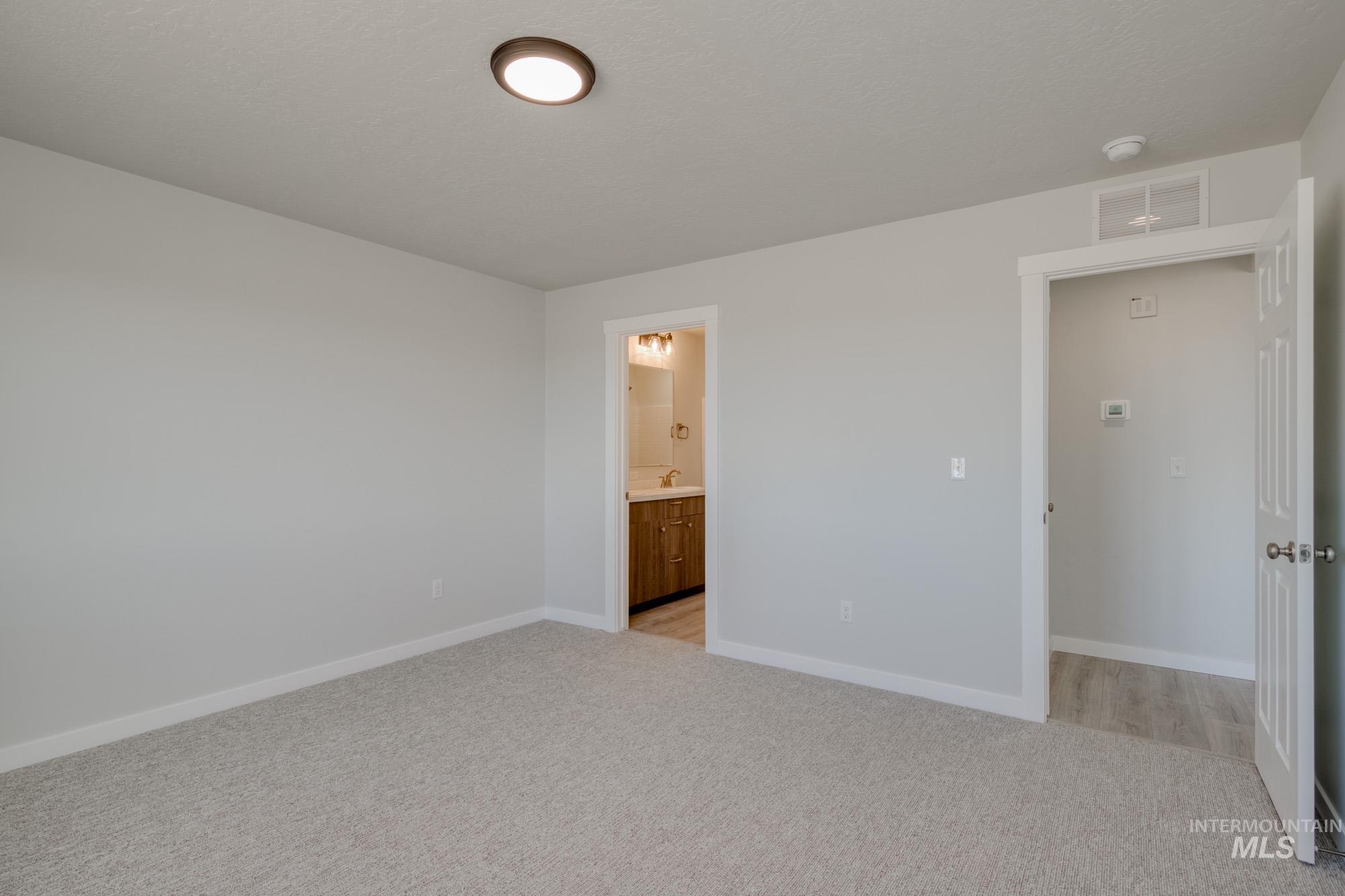 Unfurnished bedroom with light carpet and ensuite bathroom