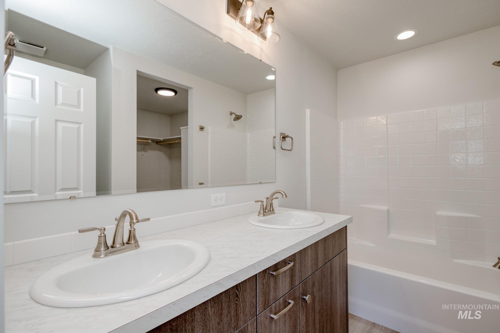 Full bathroom featuring double vanity, shower / bath combination, a spacious closet, and recessed lighting