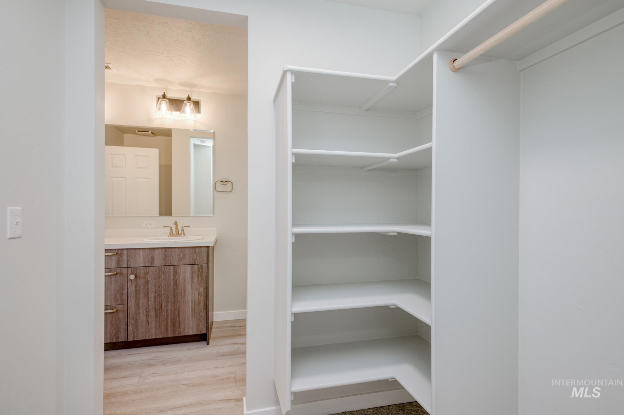 Walk in closet featuring light wood finished floors and a sink