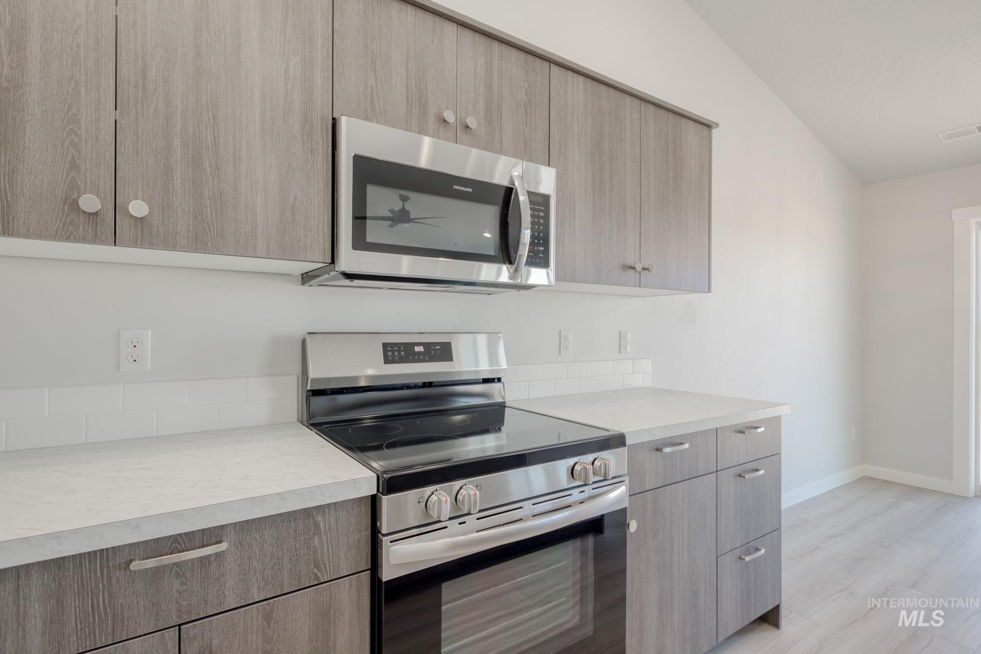 Kitchen with appliances with stainless steel finishes, modern cabinets, and light countertops