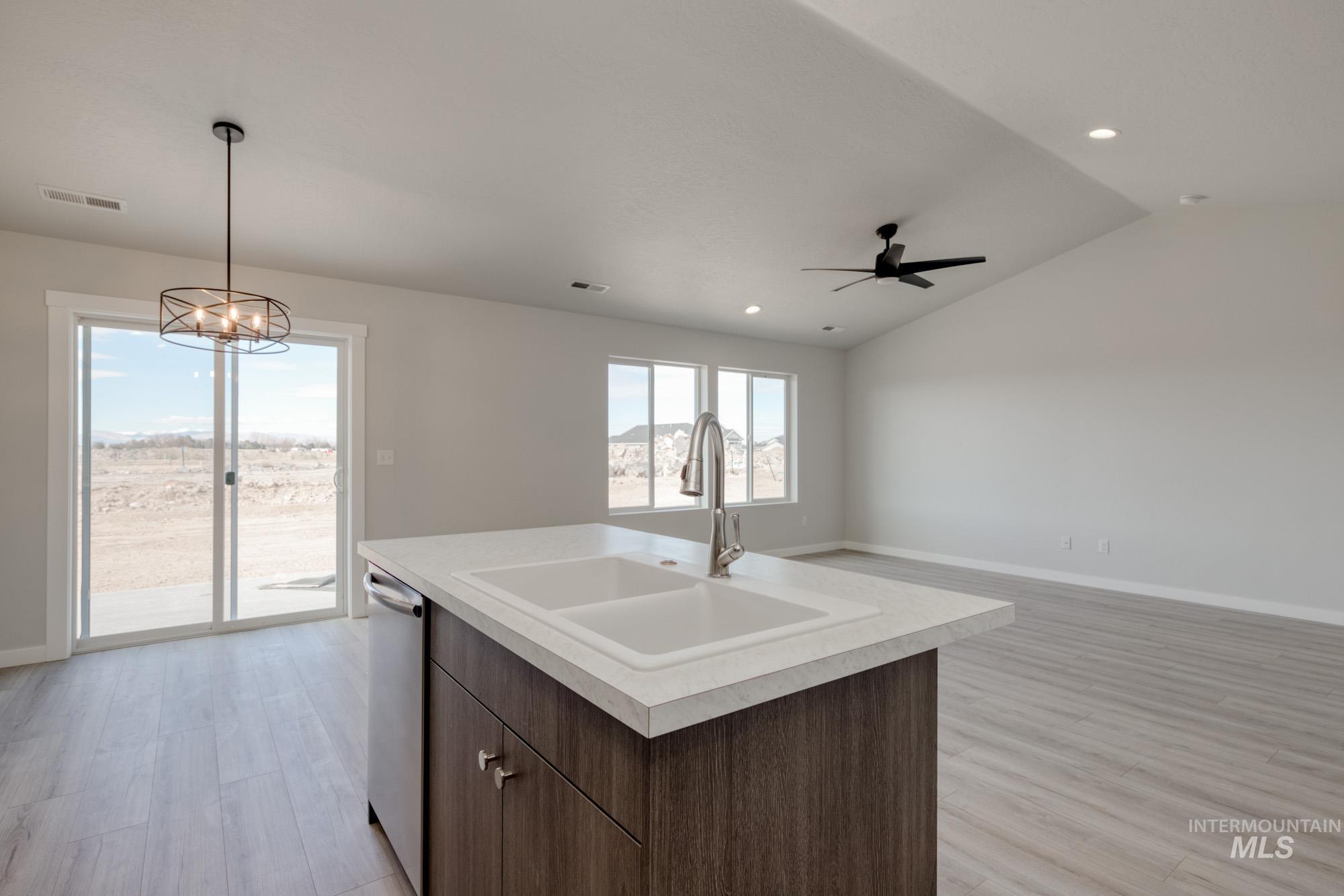 Kitchen featuring light countertops, dark brown cabinets, light wood-style floors, pendant lighting, and open floor plan