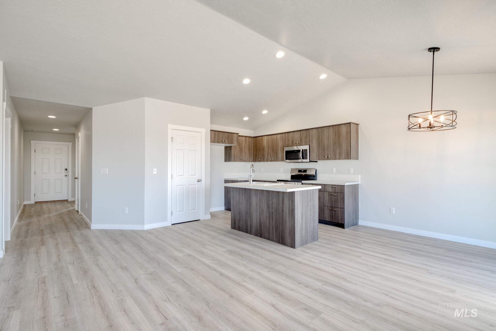 Kitchen featuring recessed lighting, open floor plan, pendant lighting, an island with sink, and light wood-style floors