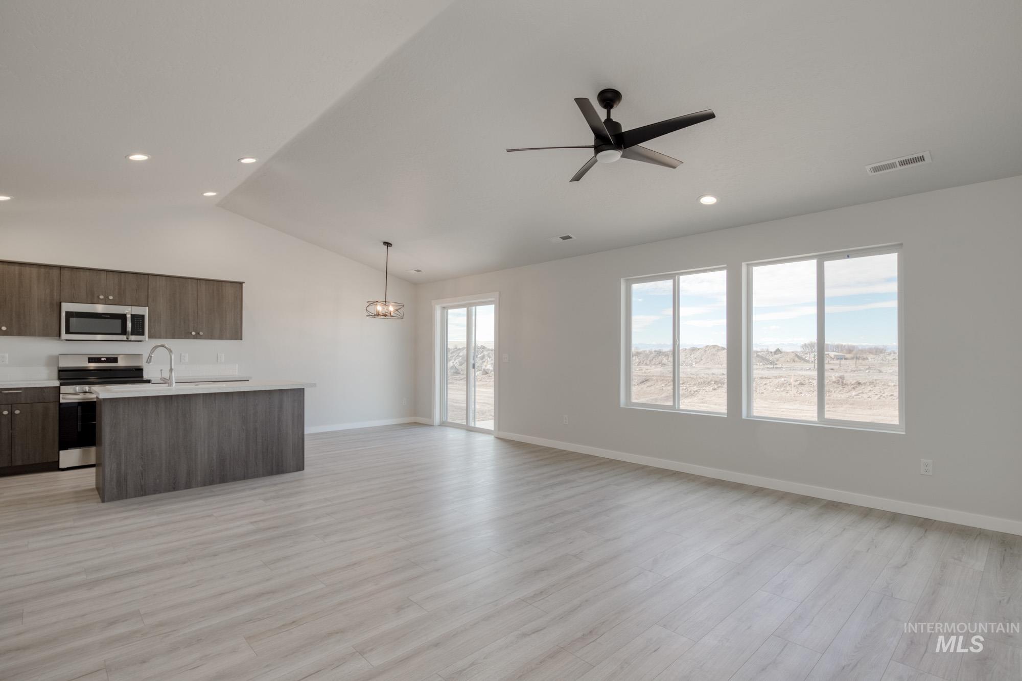 Unfurnished living room featuring lofted ceiling, light wood finished floors, ceiling fan, and recessed lighting