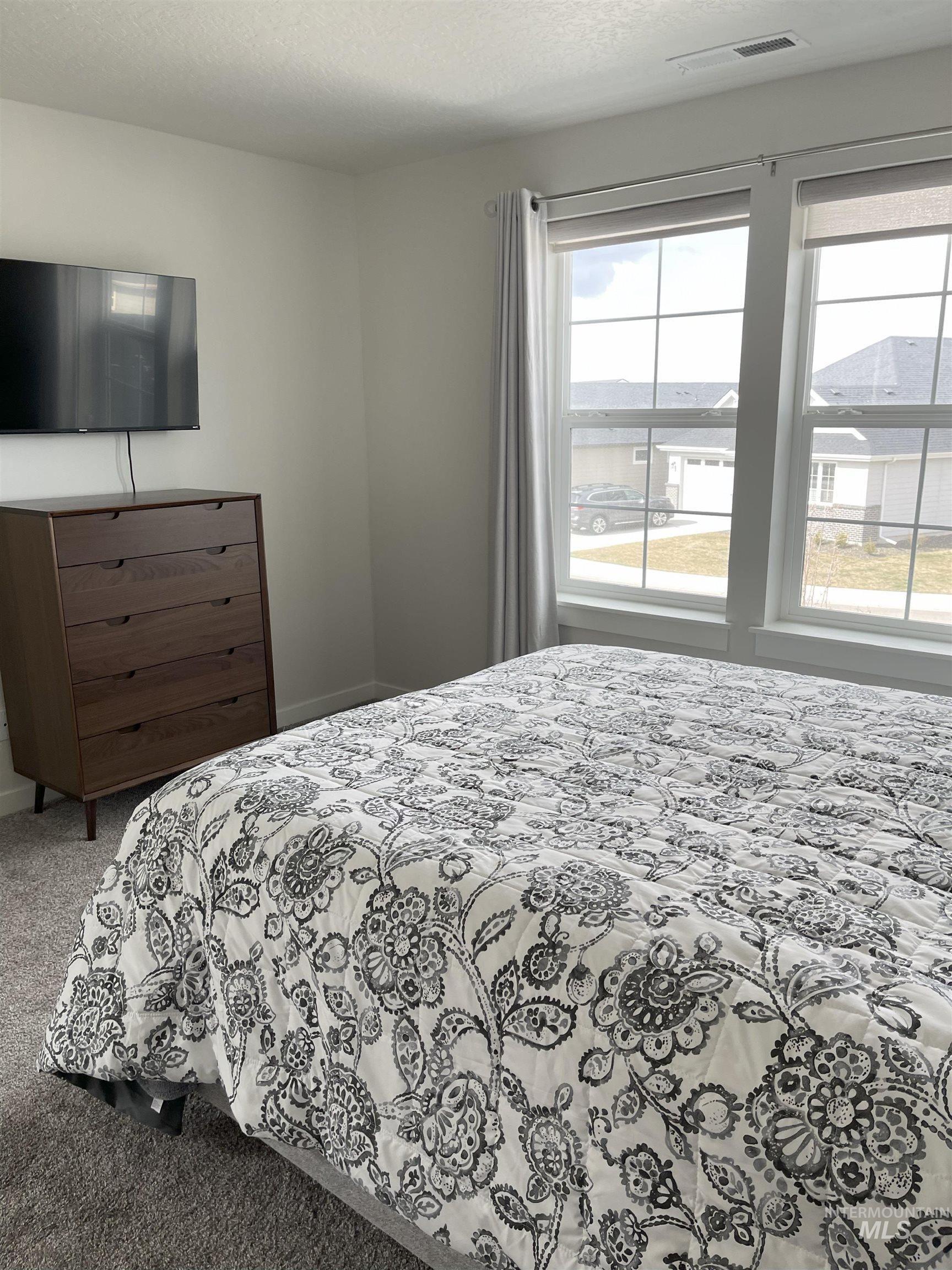 Carpeted bedroom with a textured ceiling and baseboards