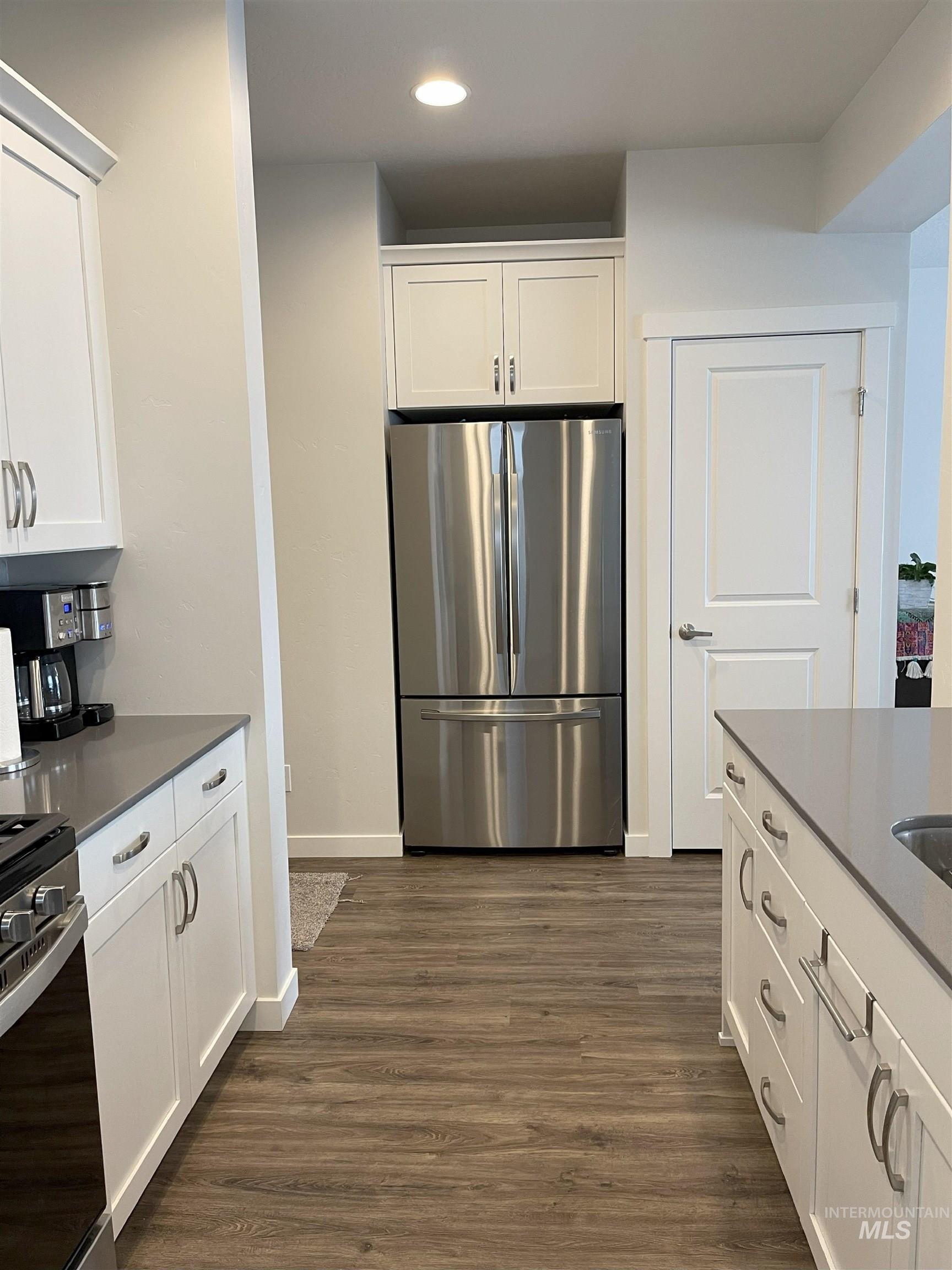 Kitchen with freestanding refrigerator, white cabinetry, range, recessed lighting, and dark wood-style flooring