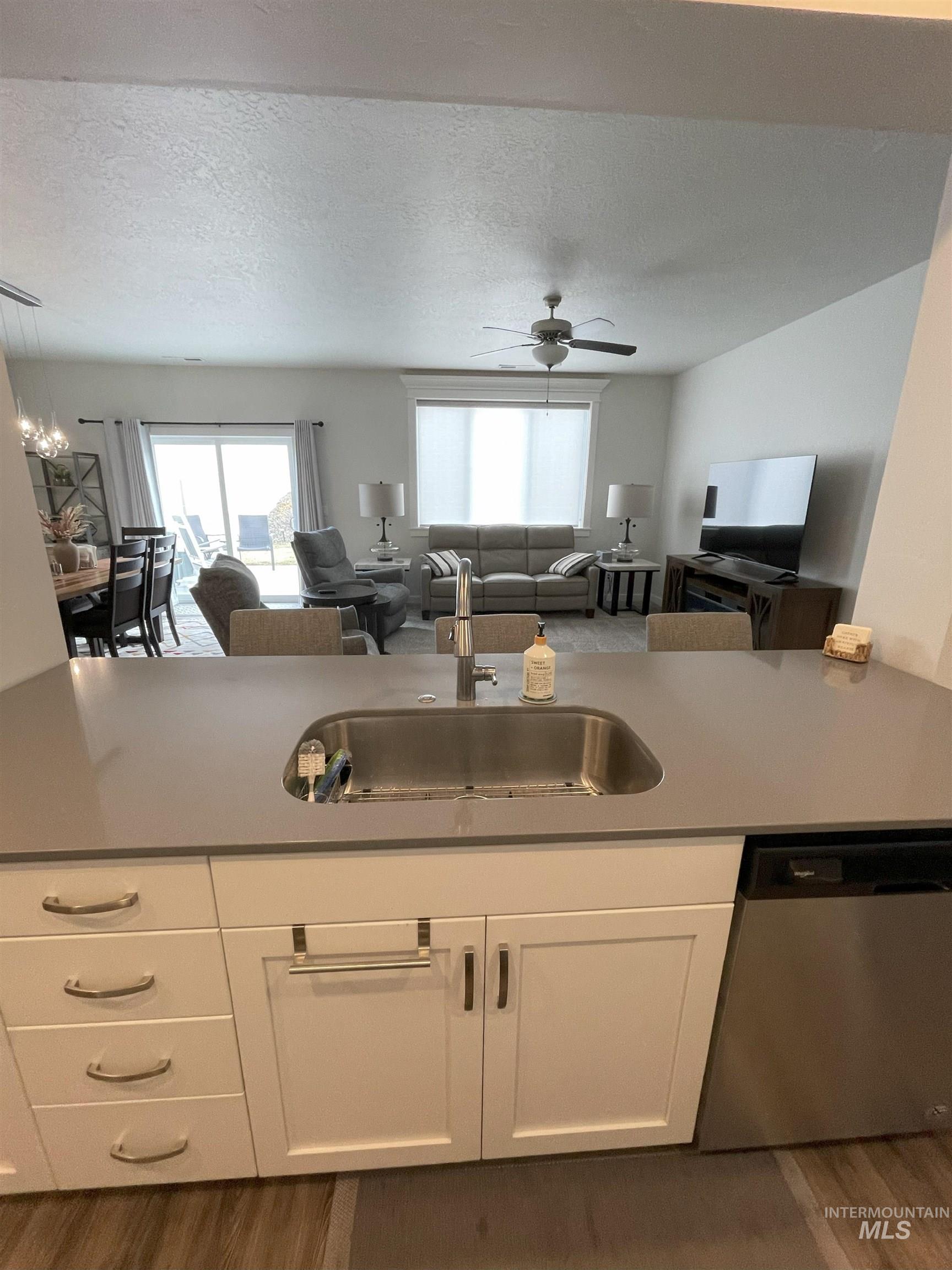 Kitchen with white cabinets, open floor plan, stainless steel dishwasher, and a textured ceiling