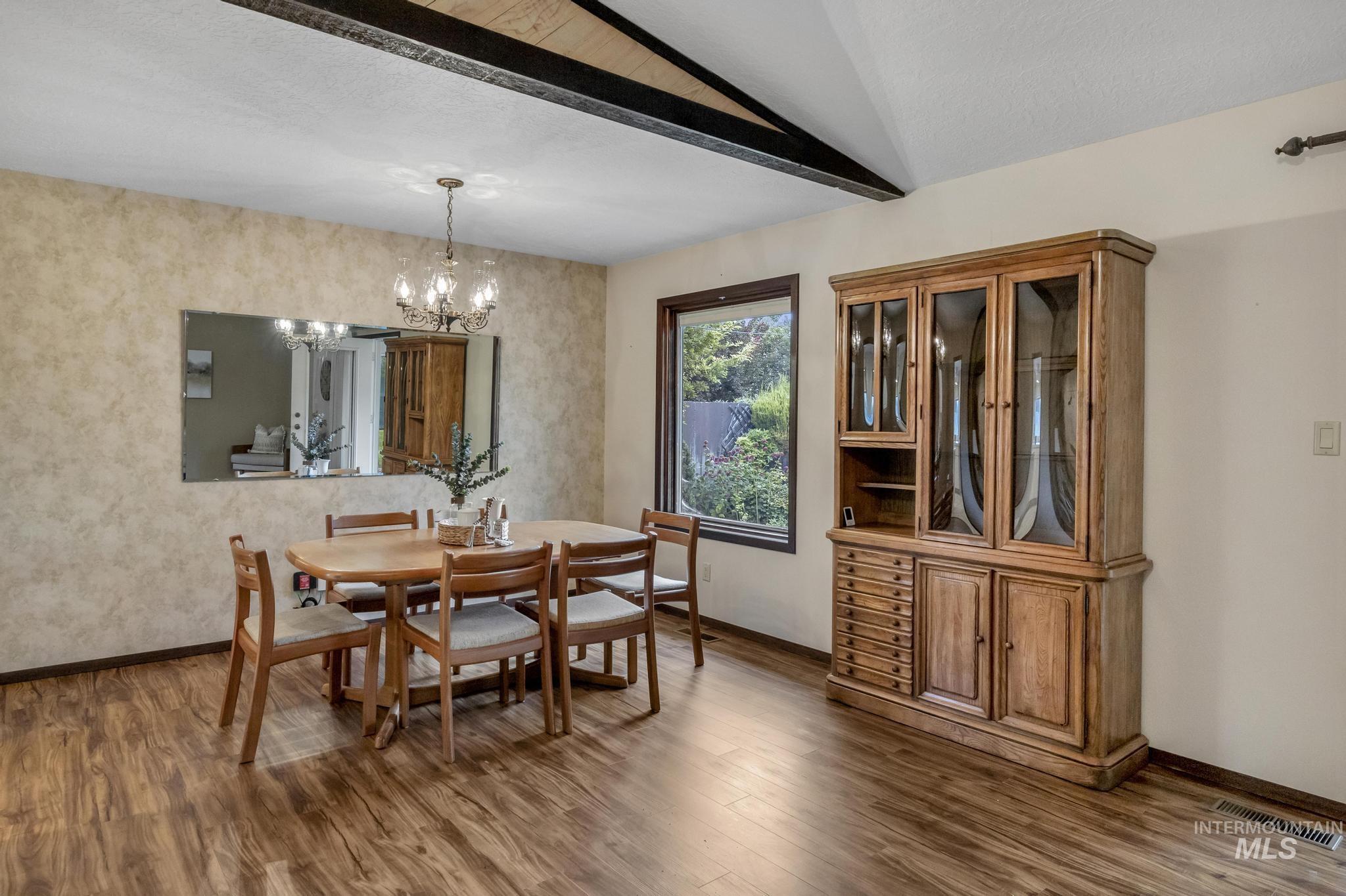 Dining room featuring dark wood-style floors, a chandelier, and a textured ceiling