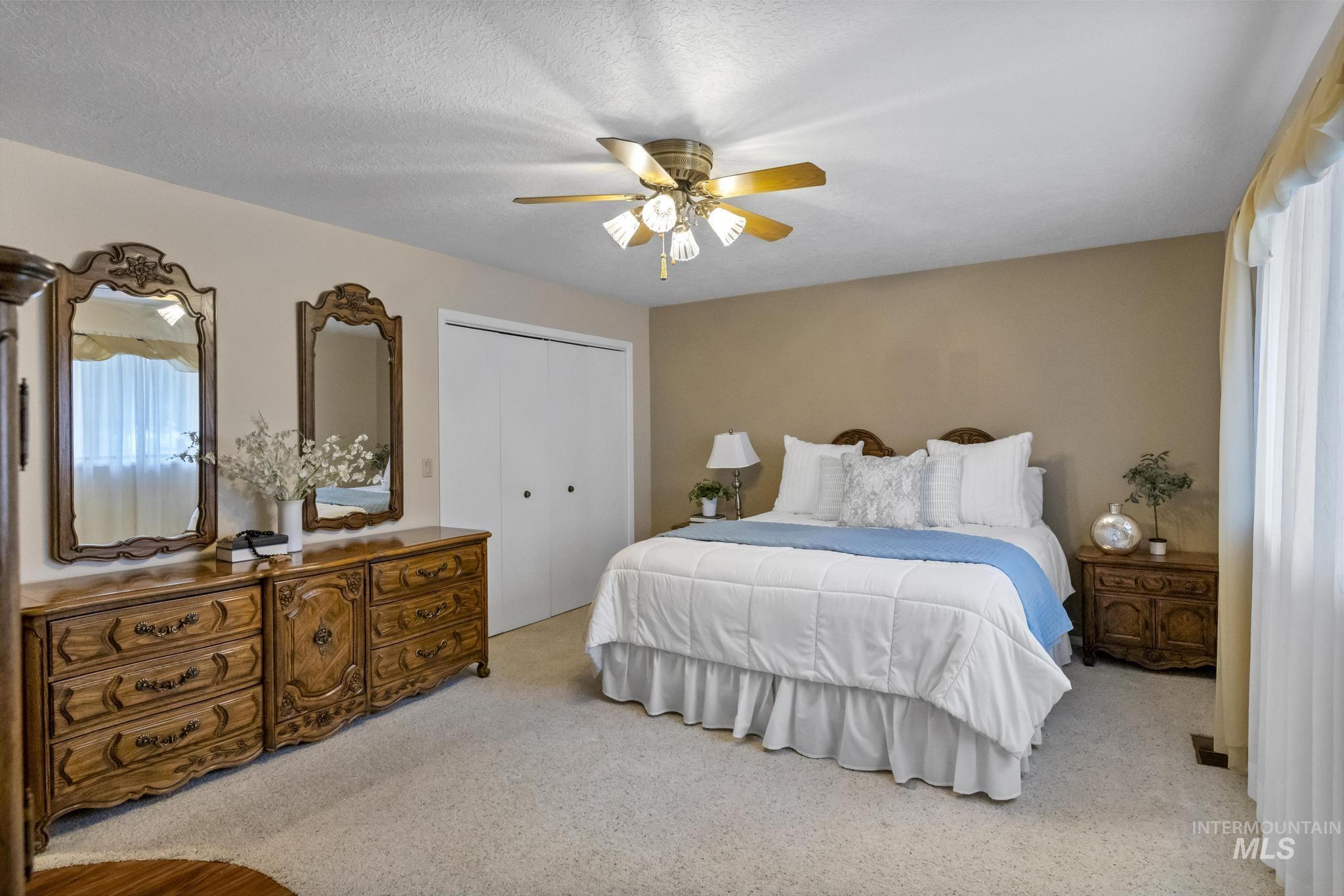 Bedroom featuring light colored carpet, ceiling fan, a closet, and a textured ceiling