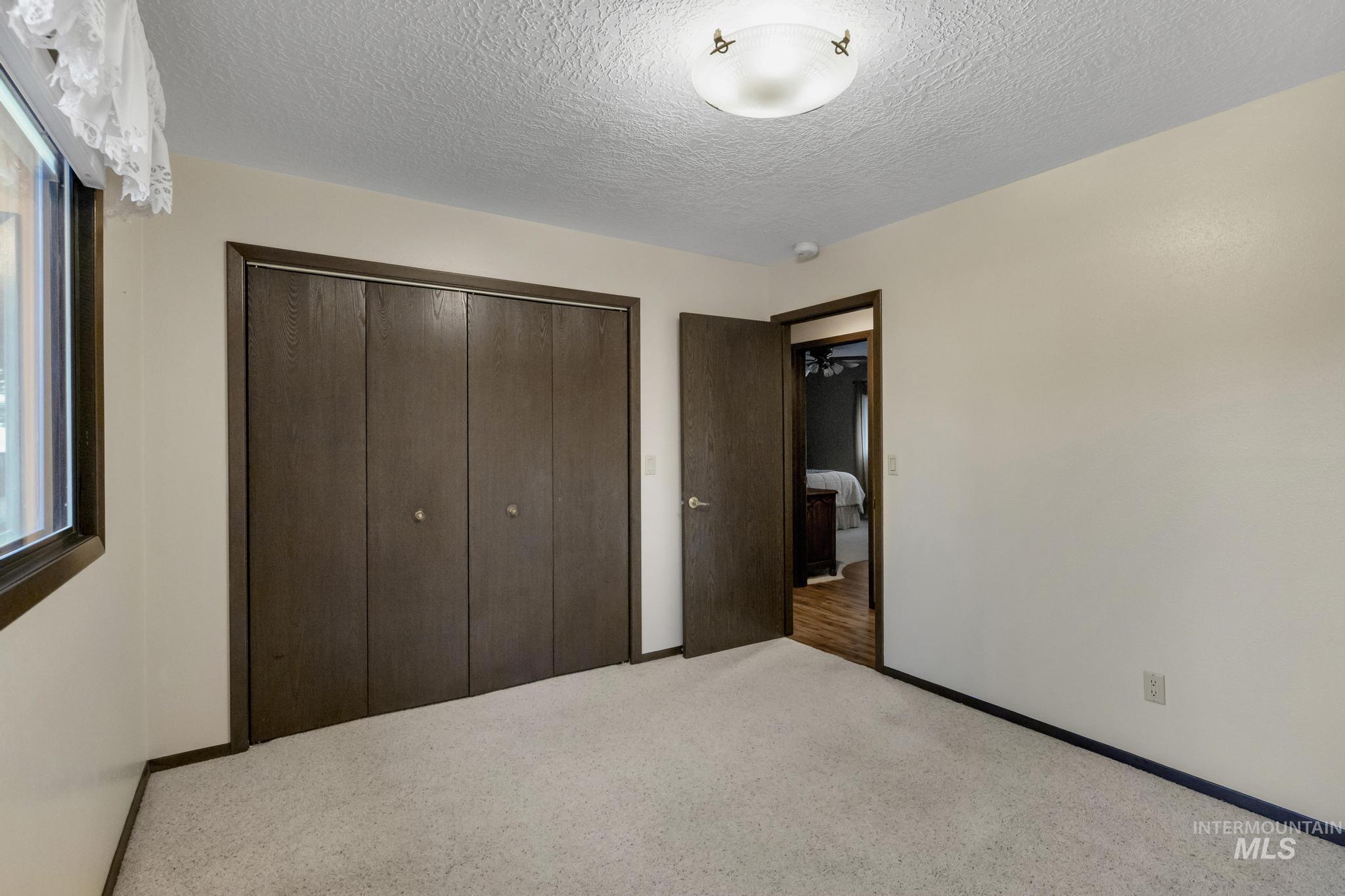 Unfurnished bedroom with a textured ceiling, carpet flooring, and a closet