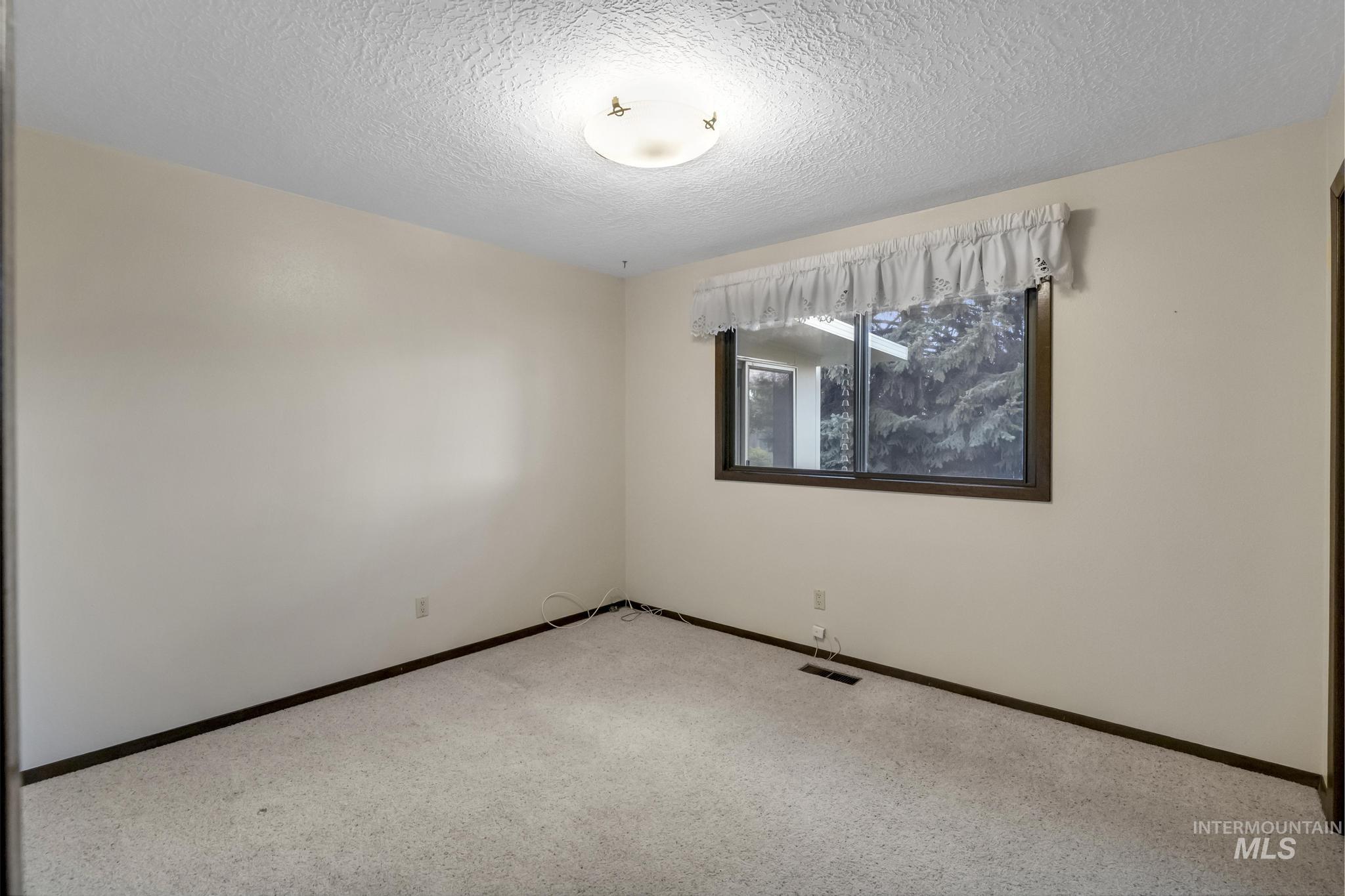 Unfurnished room featuring a textured ceiling and carpet floors