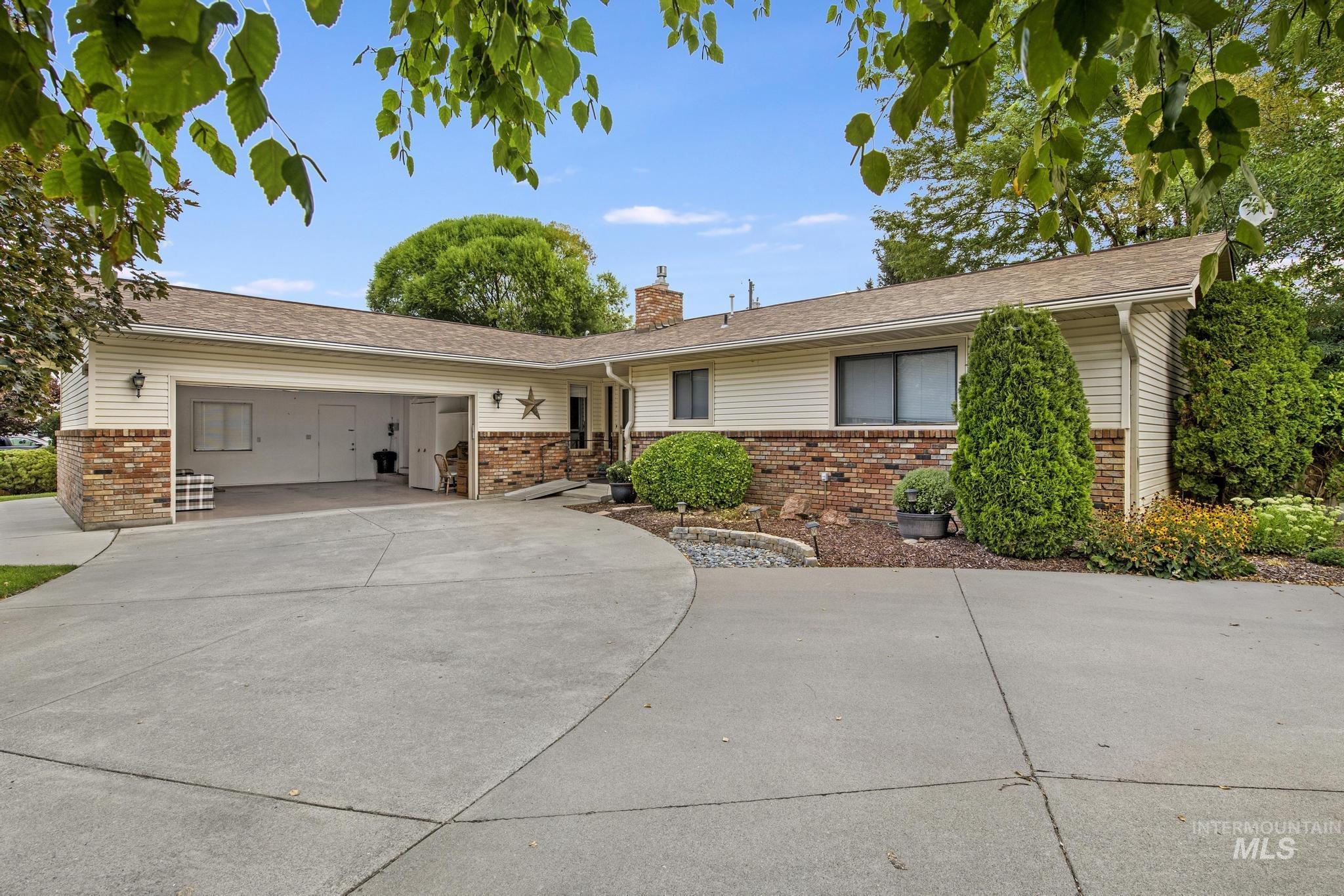 Ranch-style house with brick siding, a chimney, concrete driveway, an attached garage, and a shingled roof