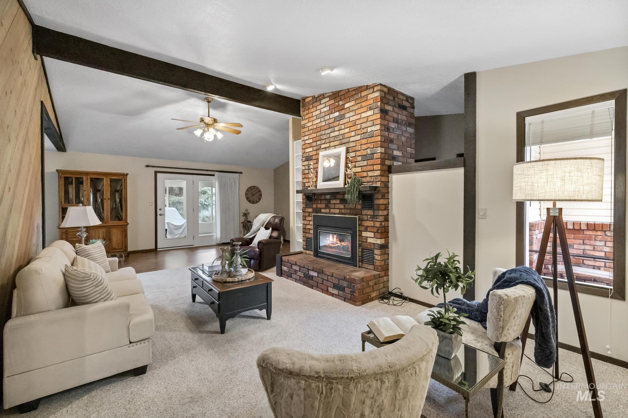 Living area with a brick fireplace, carpet, and ceiling fan