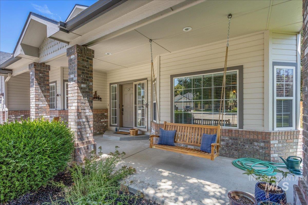 Doorway to property with a porch and brick siding
