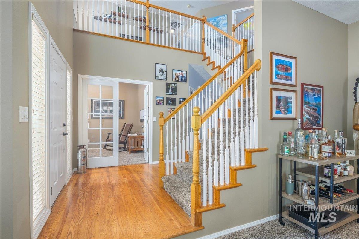 Stairway with a towering ceiling, french doors, and wood finished floors