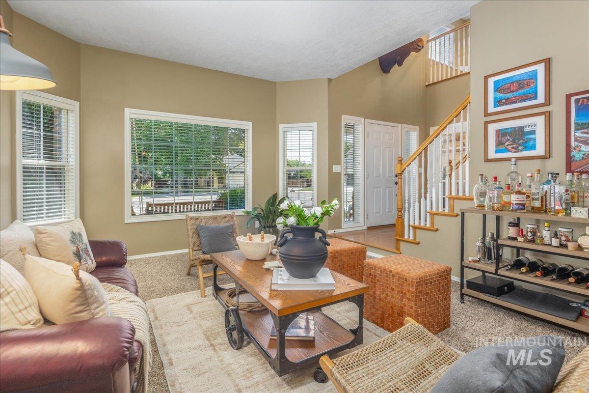Carpeted living area with stairs and baseboards