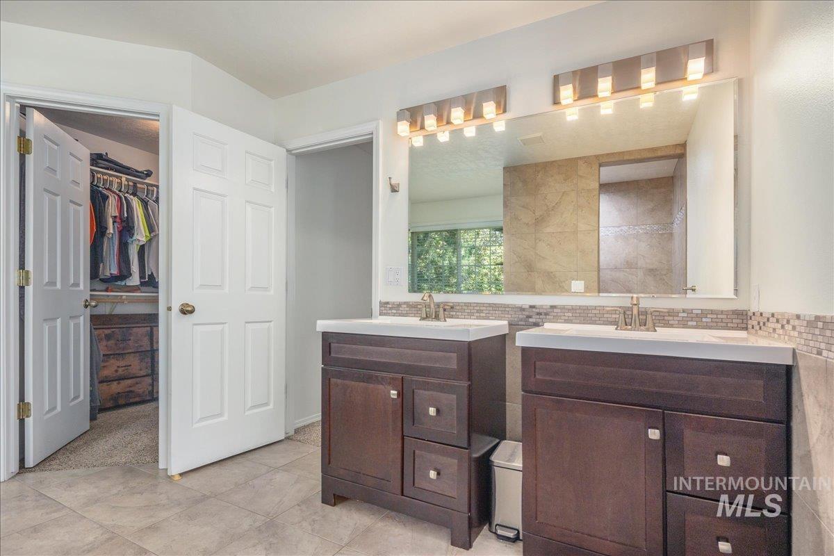 Full bathroom featuring two vanities and a walk in closet