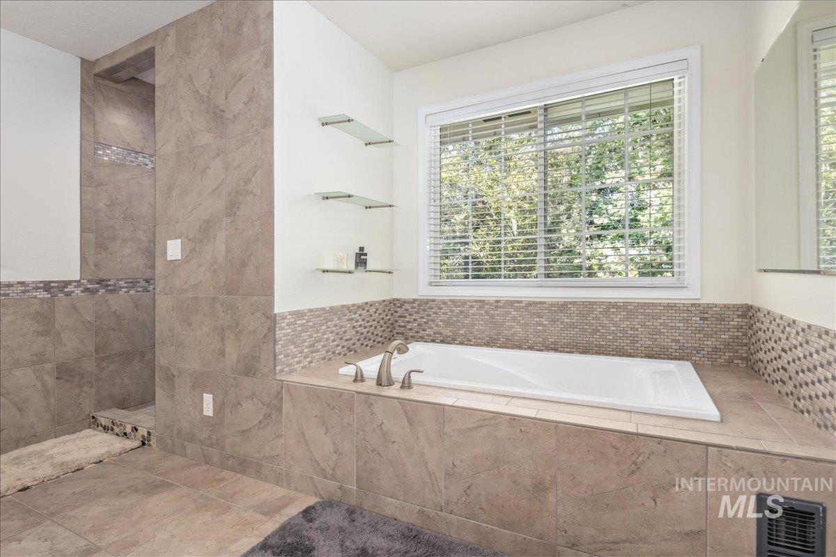 Bathroom with a garden tub, a tile shower, and tile patterned flooring