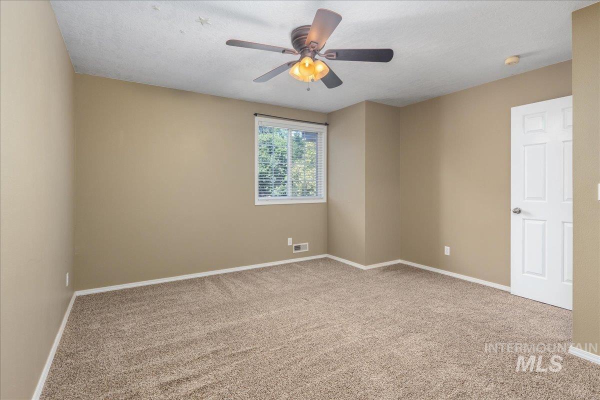 Spare room featuring a ceiling fan, carpet flooring, a smoke detector, and a textured ceiling