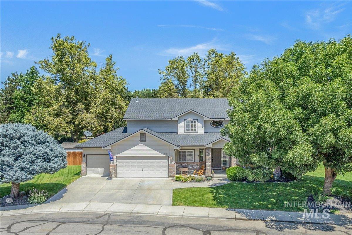 Traditional home featuring an attached garage, a front yard, concrete driveway, a porch, and brick siding