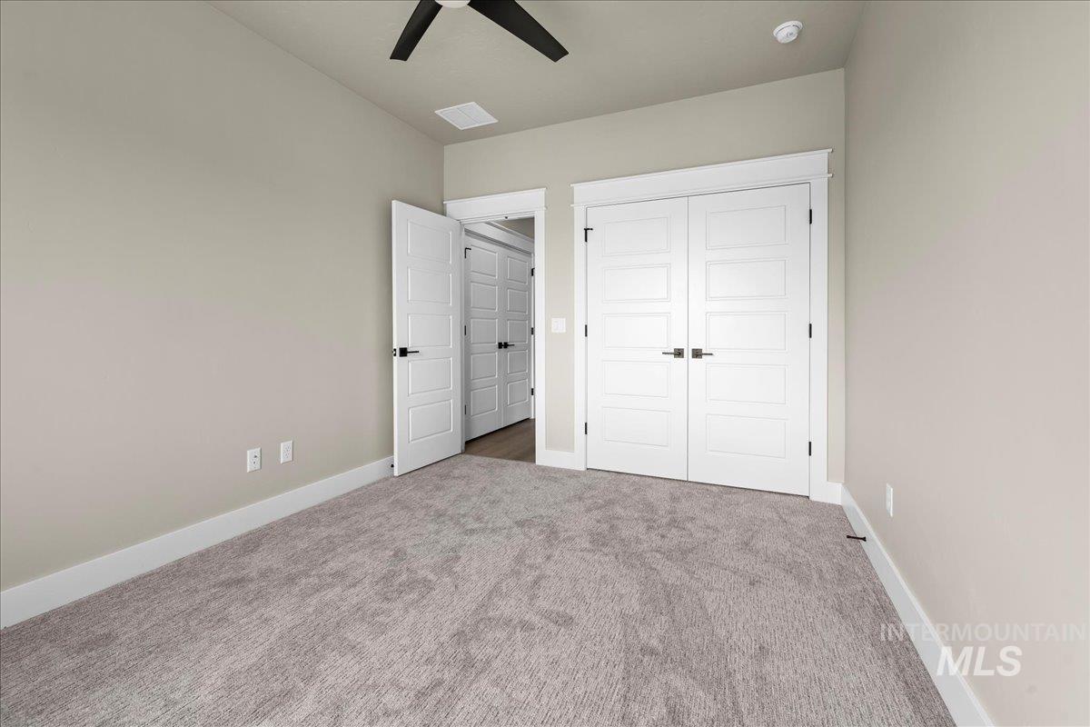 Unfurnished bedroom featuring carpet floors, a closet, and a ceiling fan