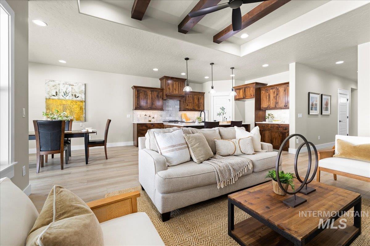 Living room featuring beamed ceiling, recessed lighting, light wood-style flooring, and a textured ceiling