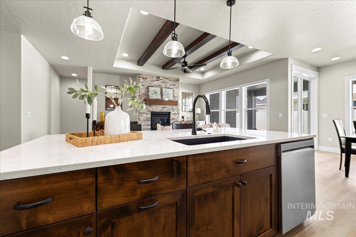 Kitchen featuring ceiling fan, a textured ceiling, light stone countertops, beam ceiling, and dark brown cabinets