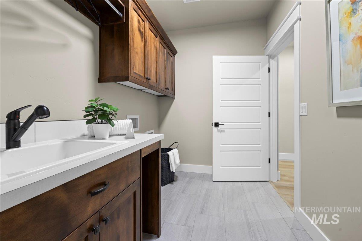 Laundry area with washer hookup, cabinet space, and light wood finished floors