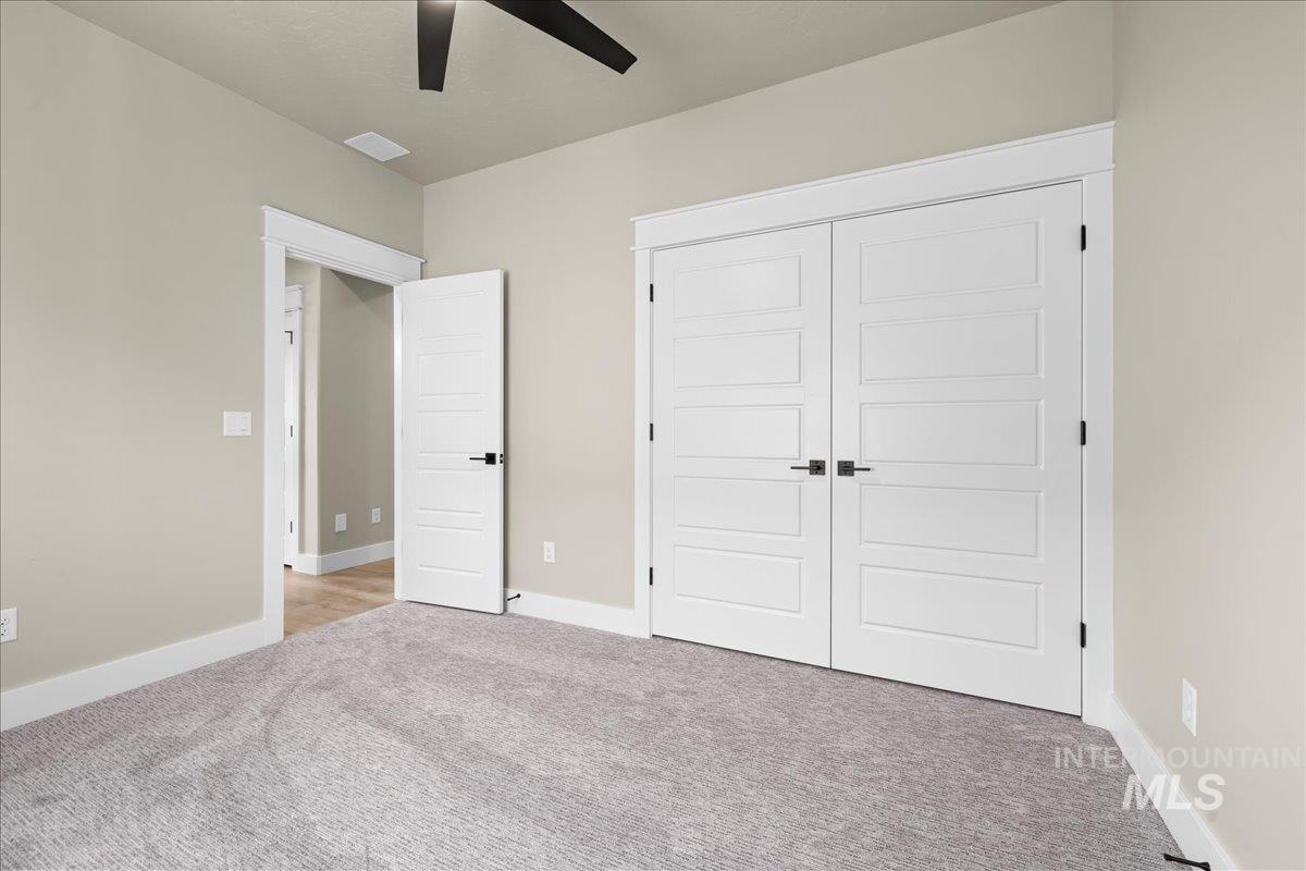 Unfurnished bedroom with light colored carpet, a closet, and a ceiling fan