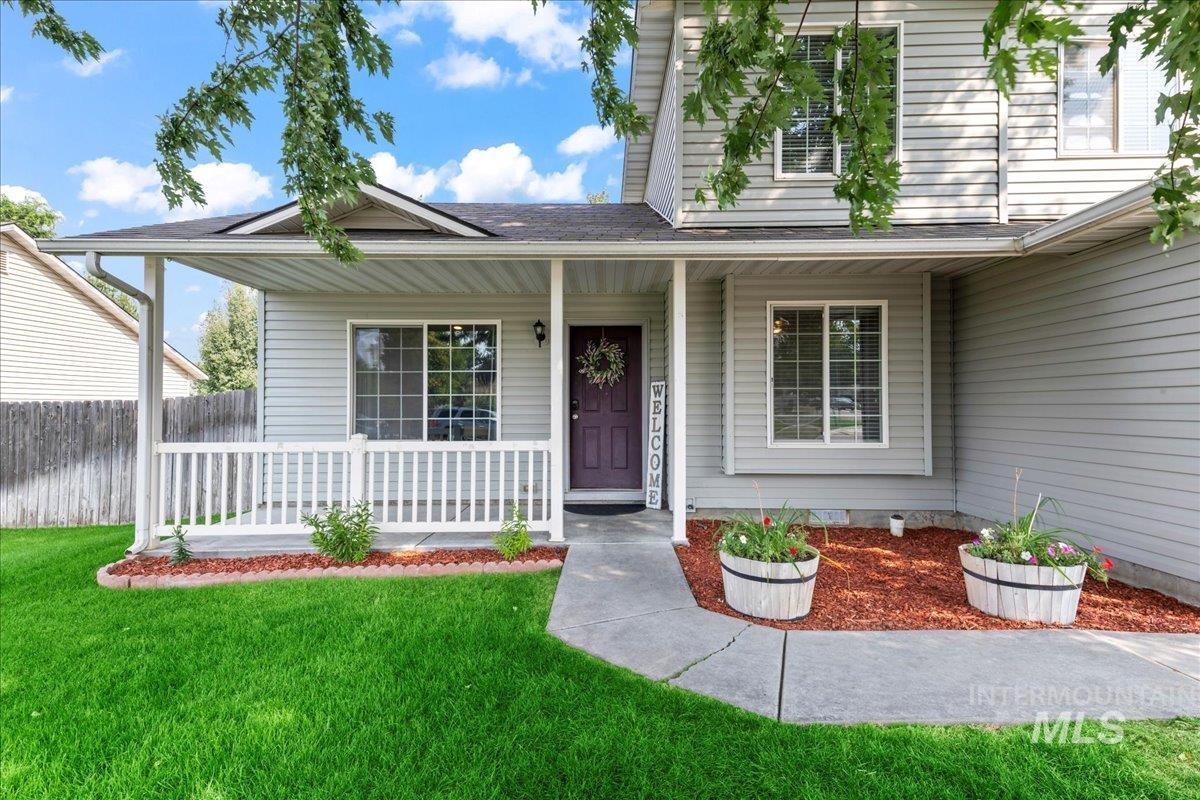 Entrance to property with covered porch, a lawn, and a shingled roo
