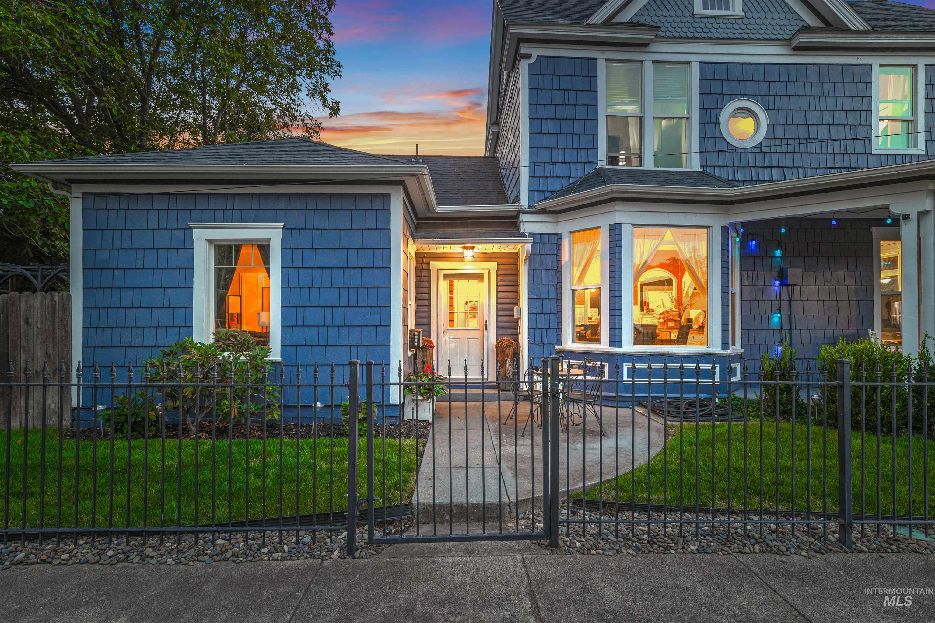 View of front of property featuring a fenced front yard, a gate, and a shingled roof