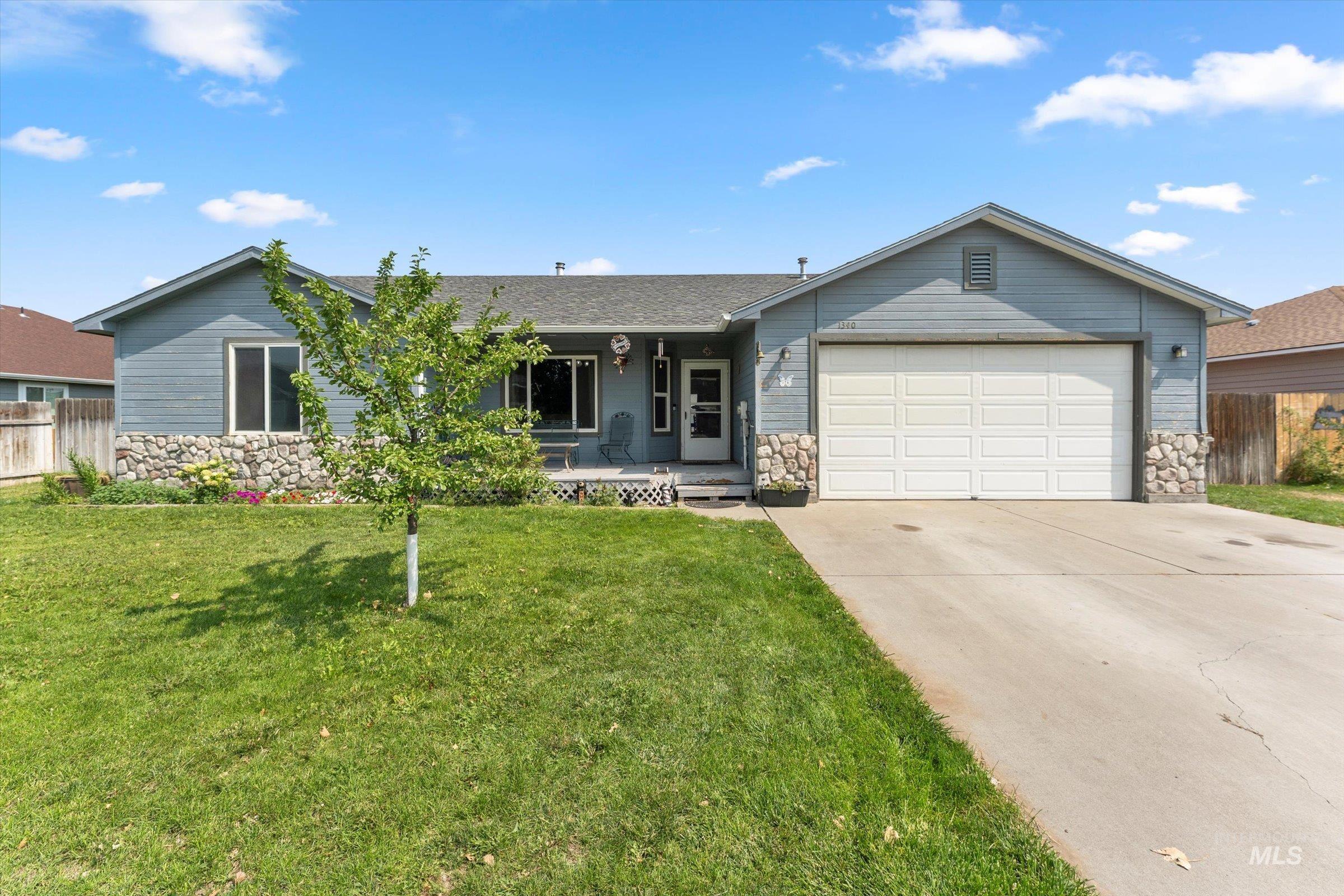 Single story home with stone siding, a porch, driveway, and an attached garage