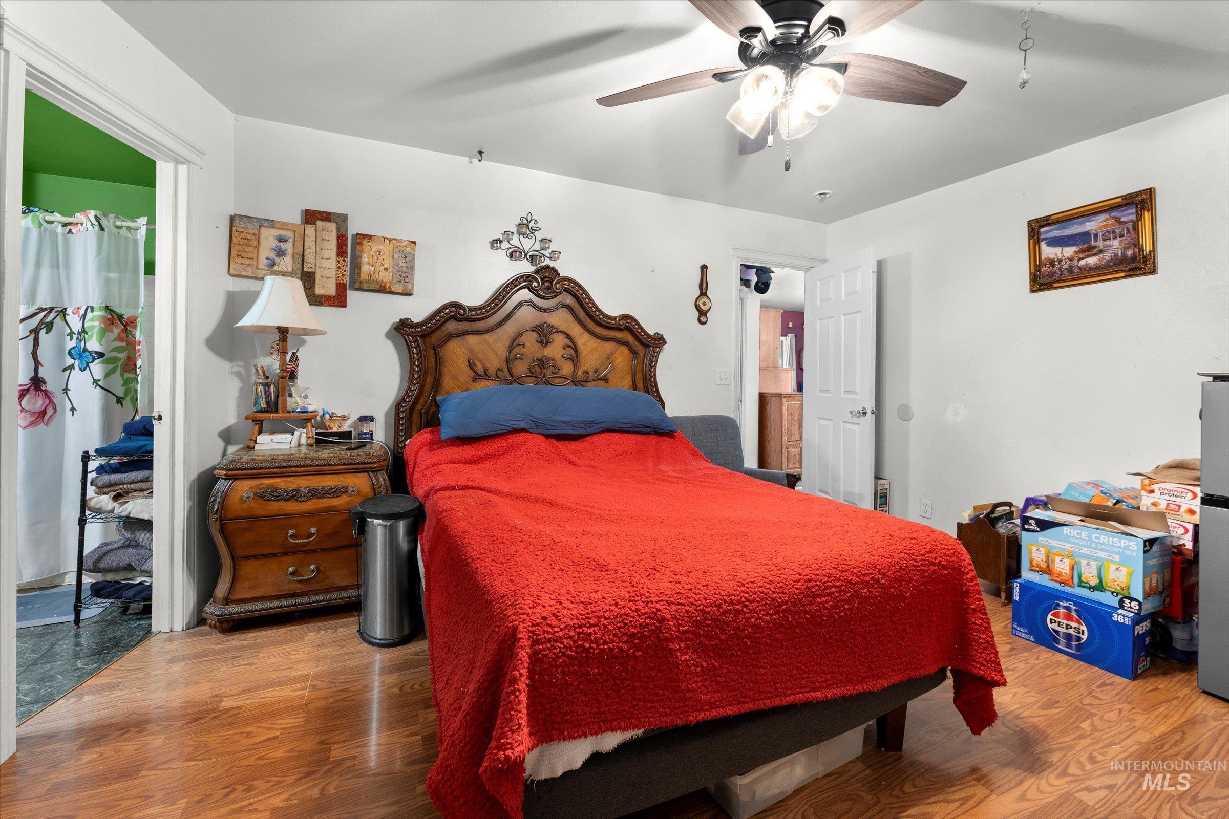 Bedroom with light wood finished floors, a ceiling fan, and freestanding refrigerator