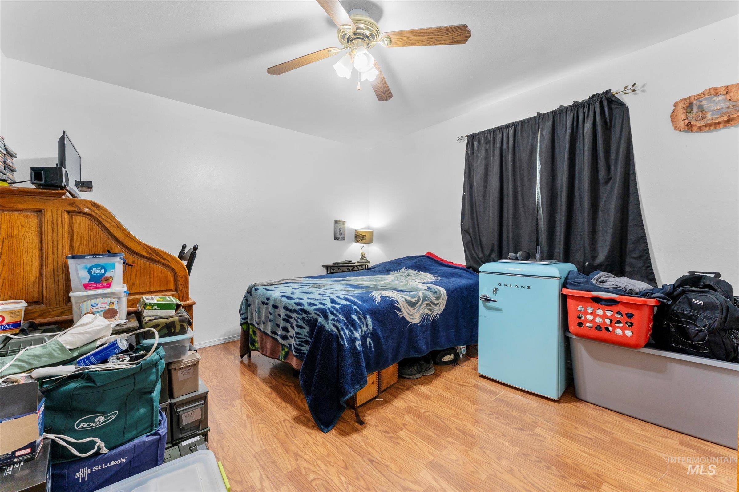 Bedroom featuring wood finished floors, fridge, and ceiling fan