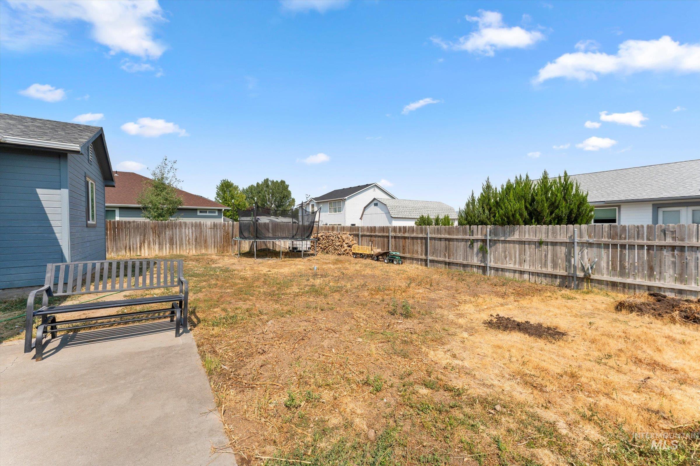 Fenced backyard featuring a trampoline