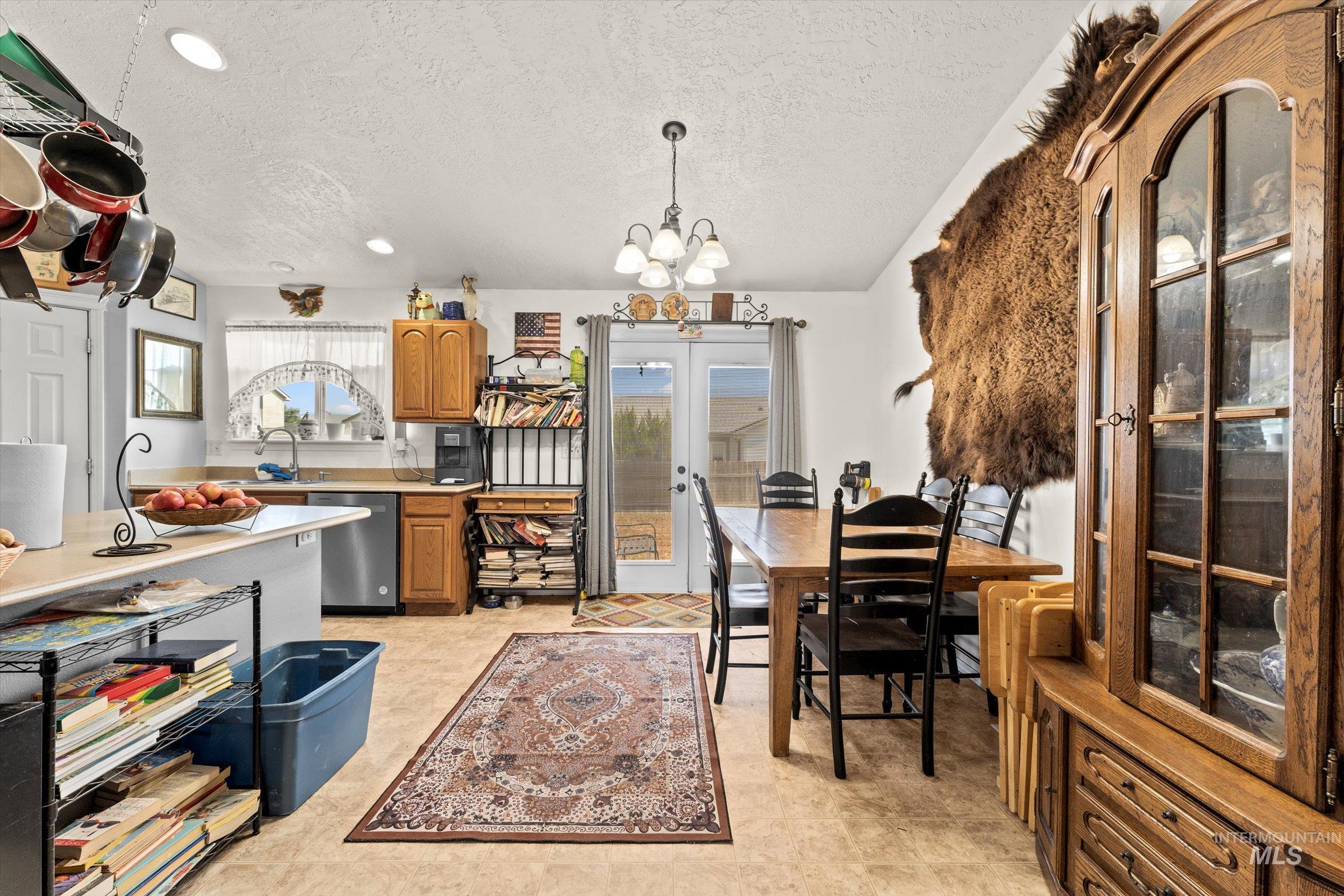 Kitchen with light countertops, dishwasher, a chandelier, a textured ceiling, and pendant lighting