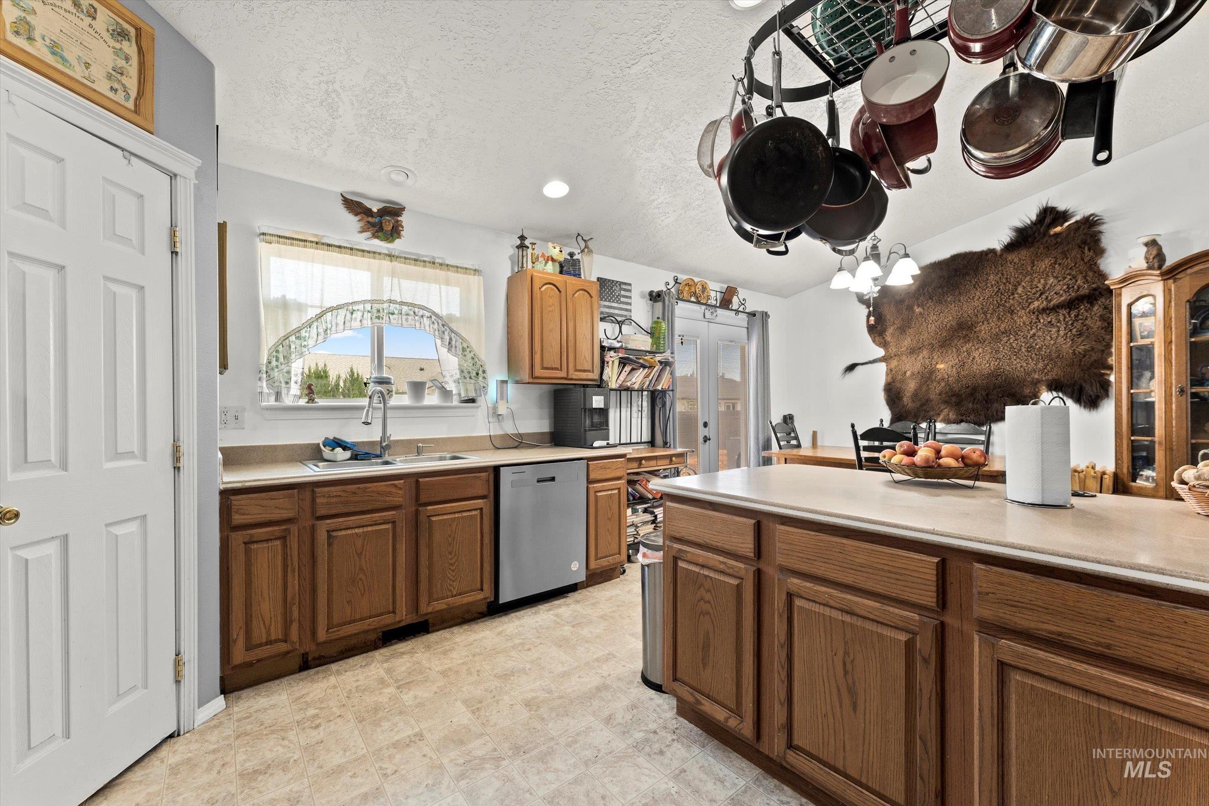 Kitchen with light countertops, dishwasher, a textured ceiling, brown cabinets, and recessed lighting
