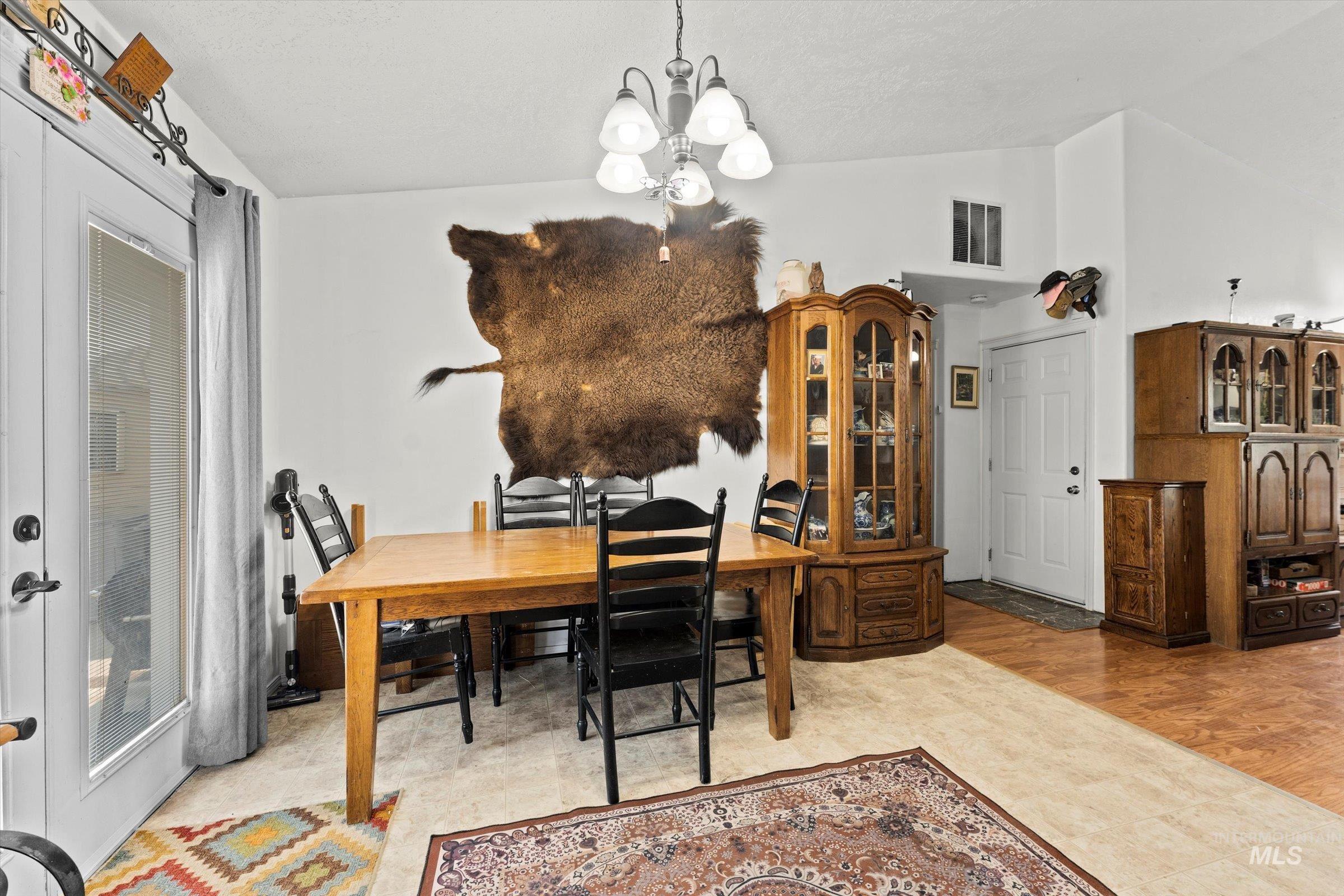 Dining area featuring vaulted ceiling, a chandelier, and light wood finished floors