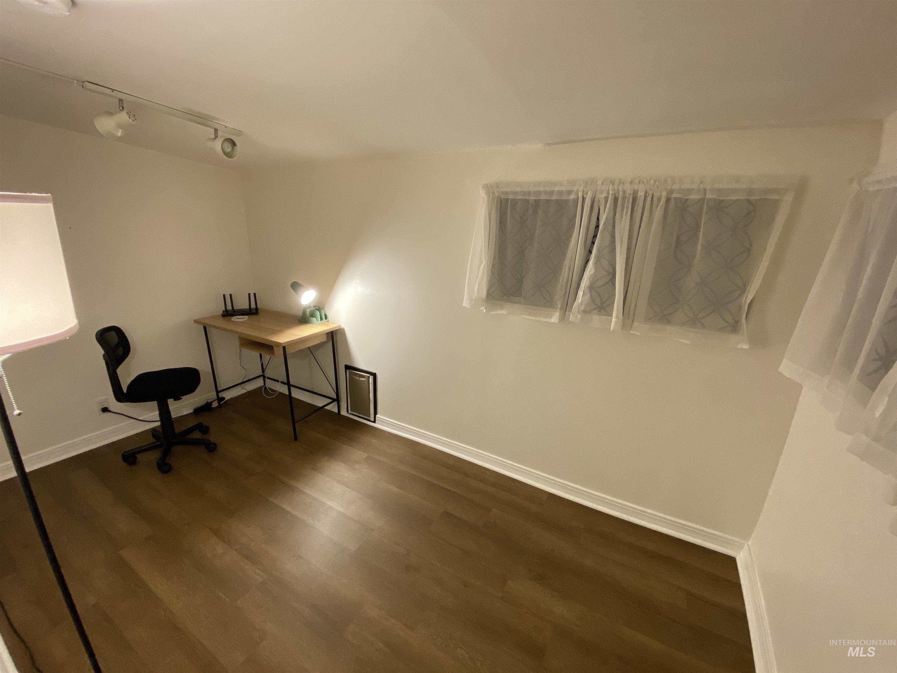 Unfurnished office featuring dark wood-style flooring and track lighting