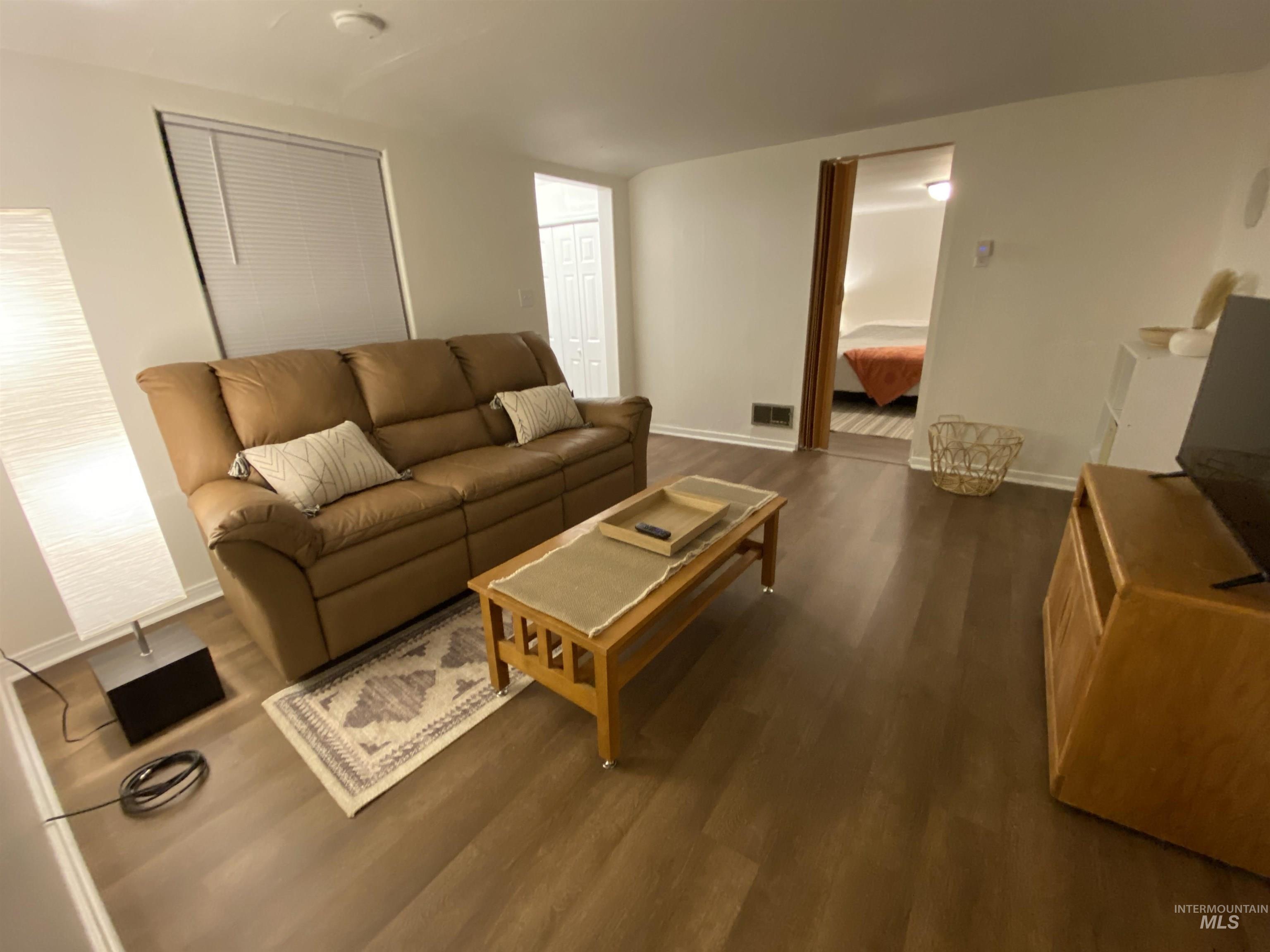 Living room featuring dark wood finished floors and baseboards