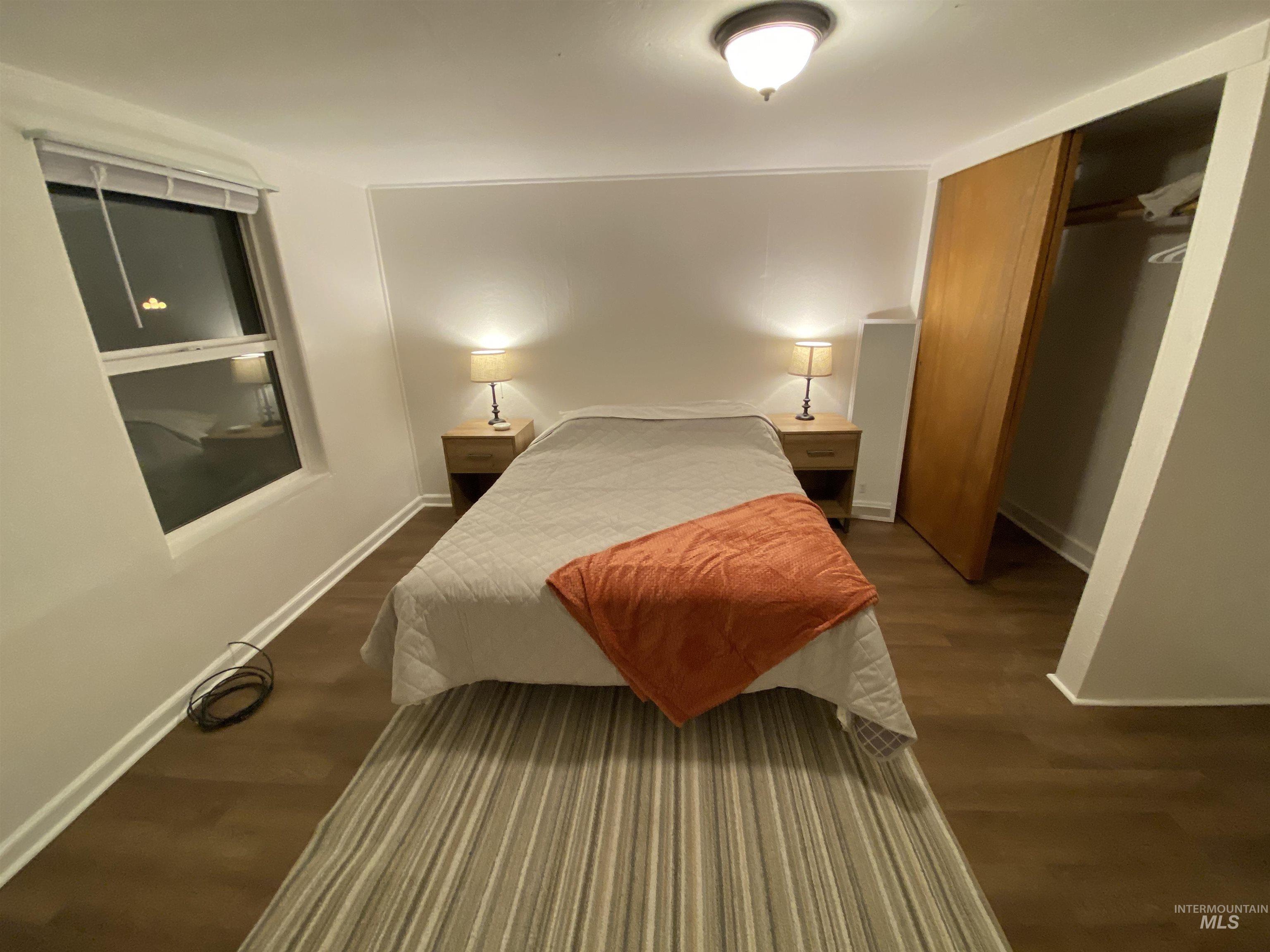 Bedroom with dark wood finished floors and a closet