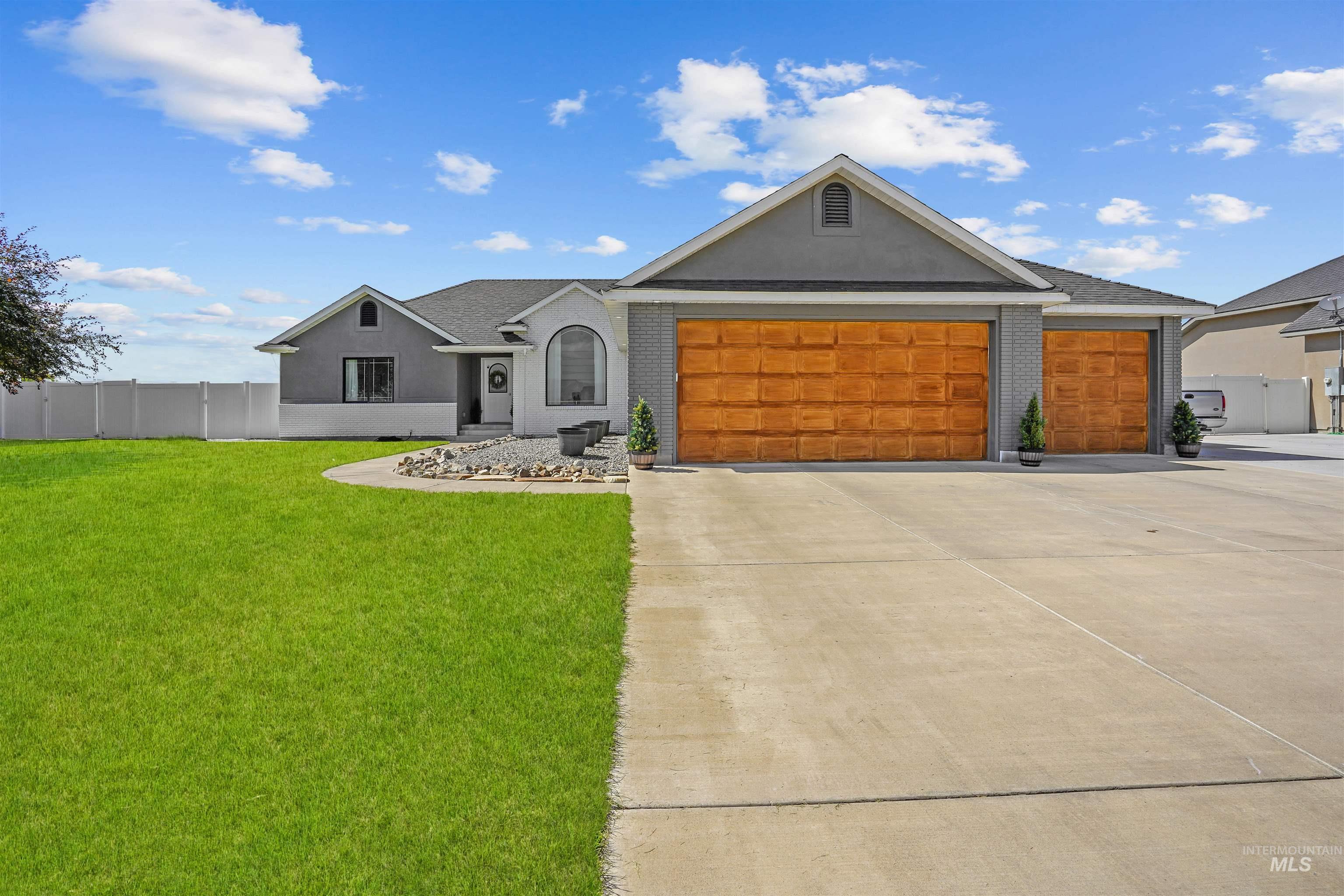 Ranch-style home with an attached garage, concrete driveway, brick siding, and stucco siding