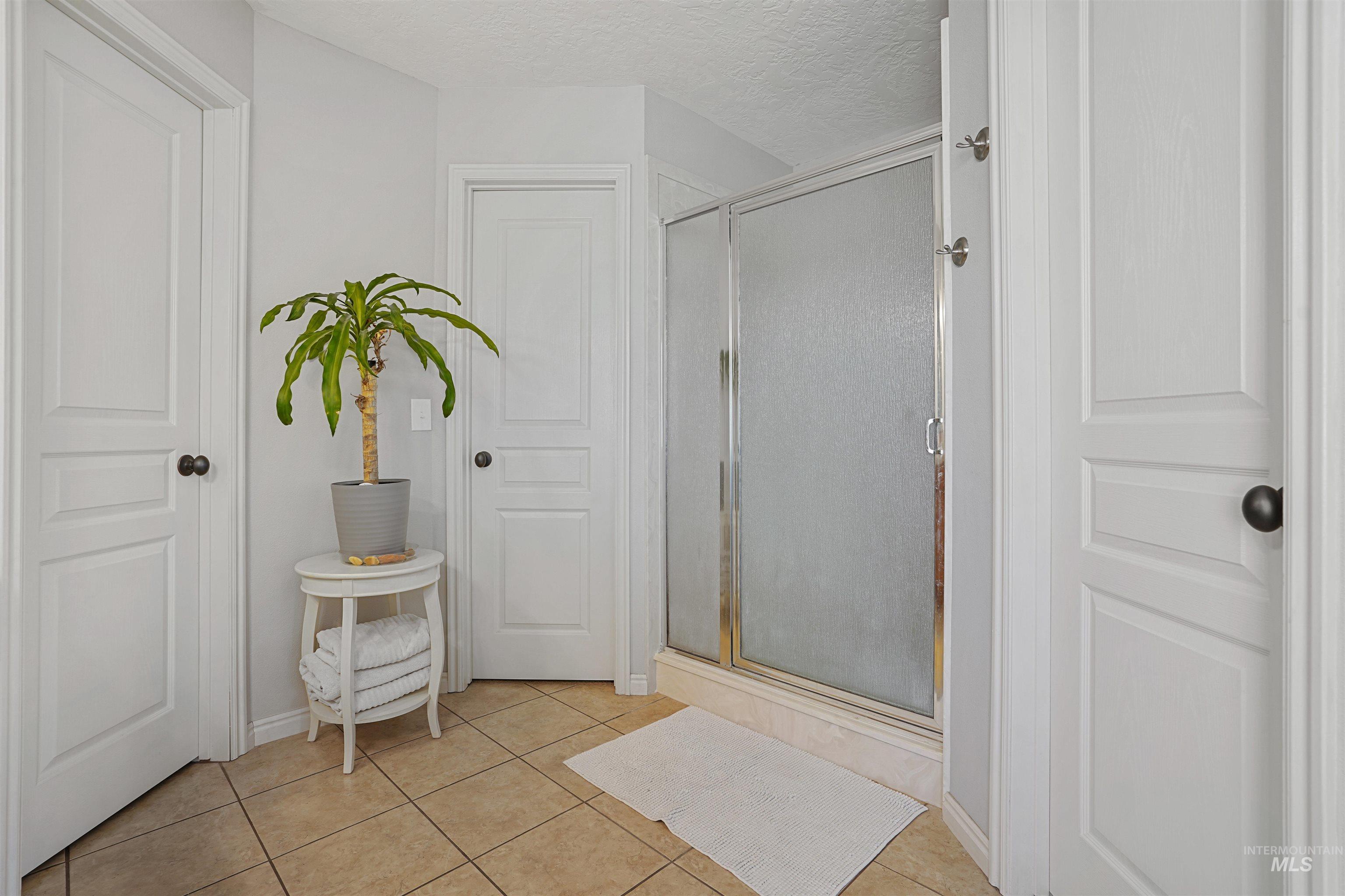 Bathroom featuring a stall shower, a textured ceiling, and light tile patterned floors