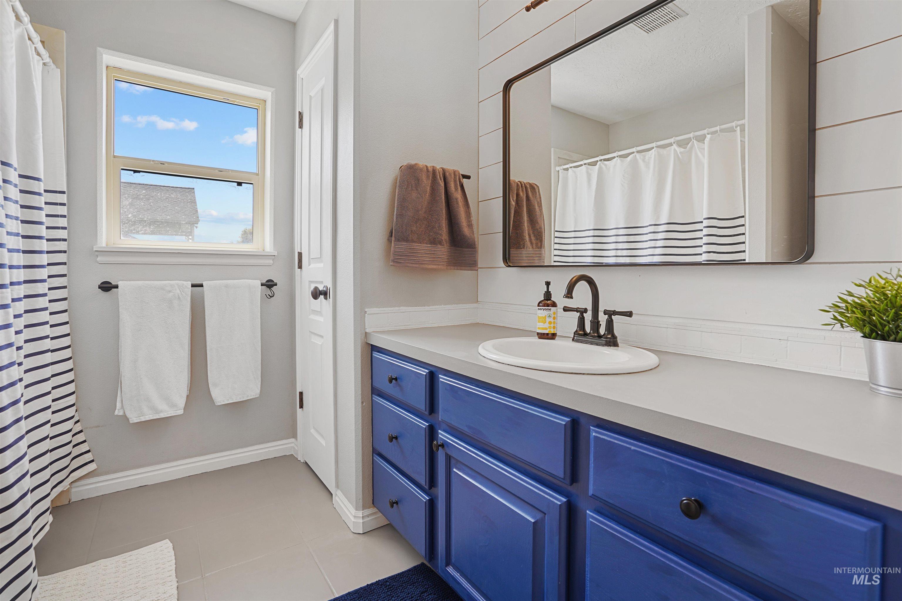 Full bath with vanity, light tile patterned flooring, and a shower with shower curtain