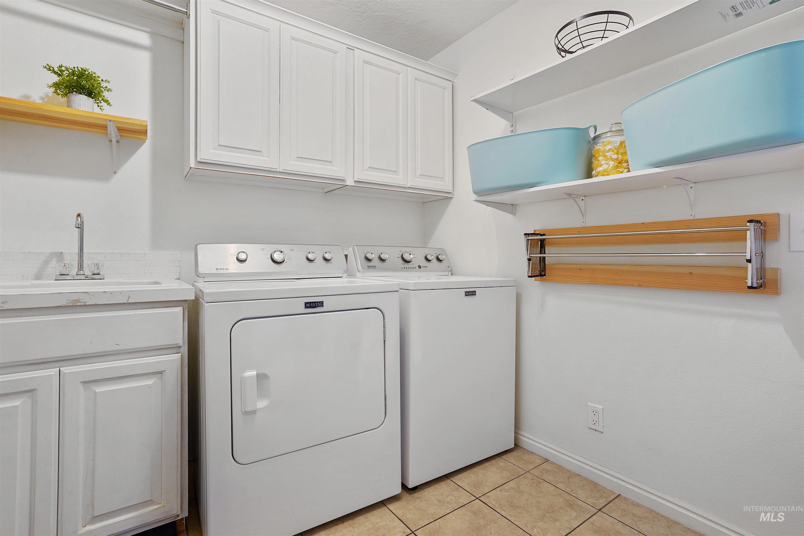 Laundry room featuring light tile patterned floors, cabinet space, and washer and dryer