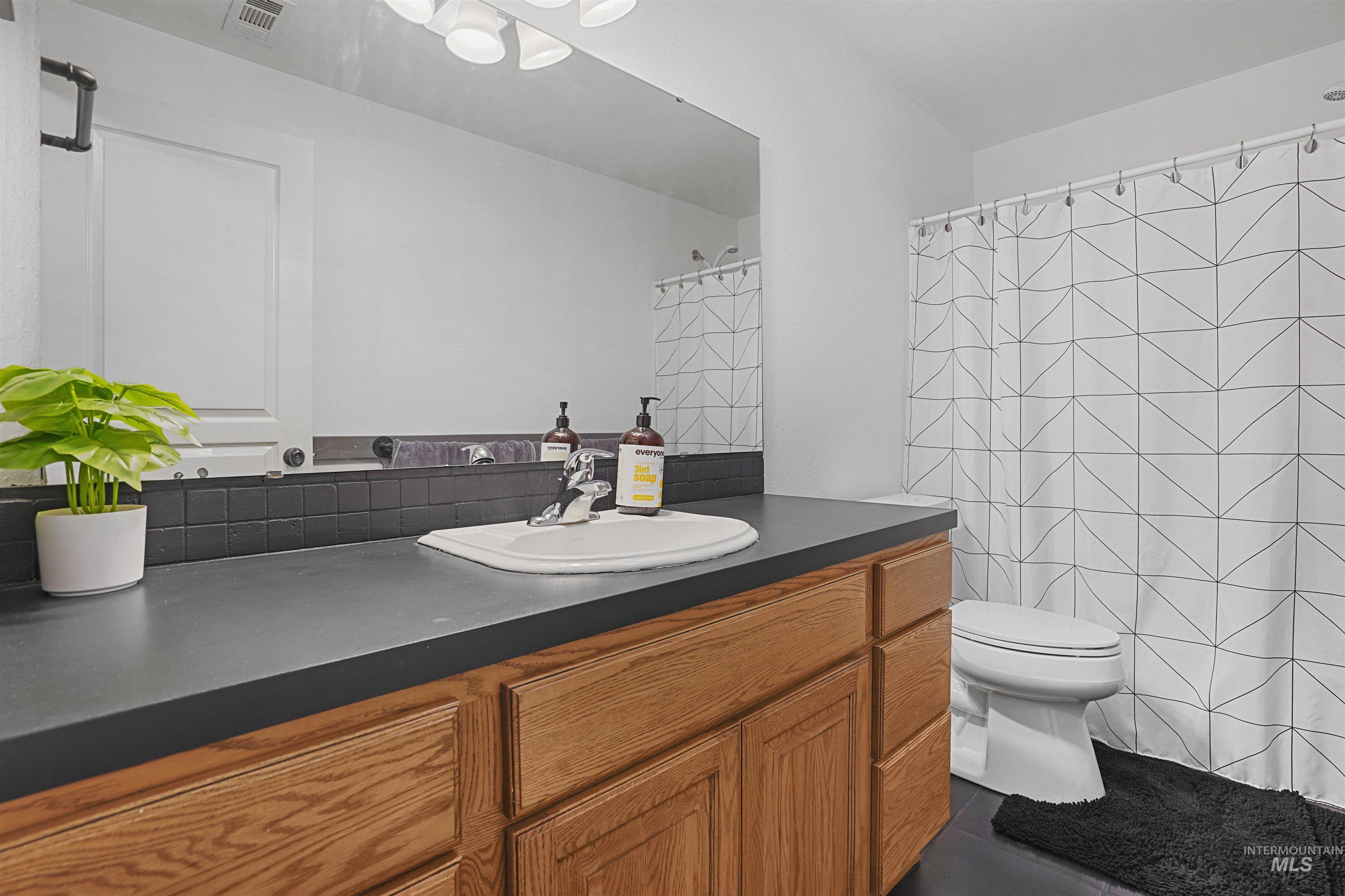 Bathroom with vanity, a shower with shower curtain, and dark tile patterned flooring