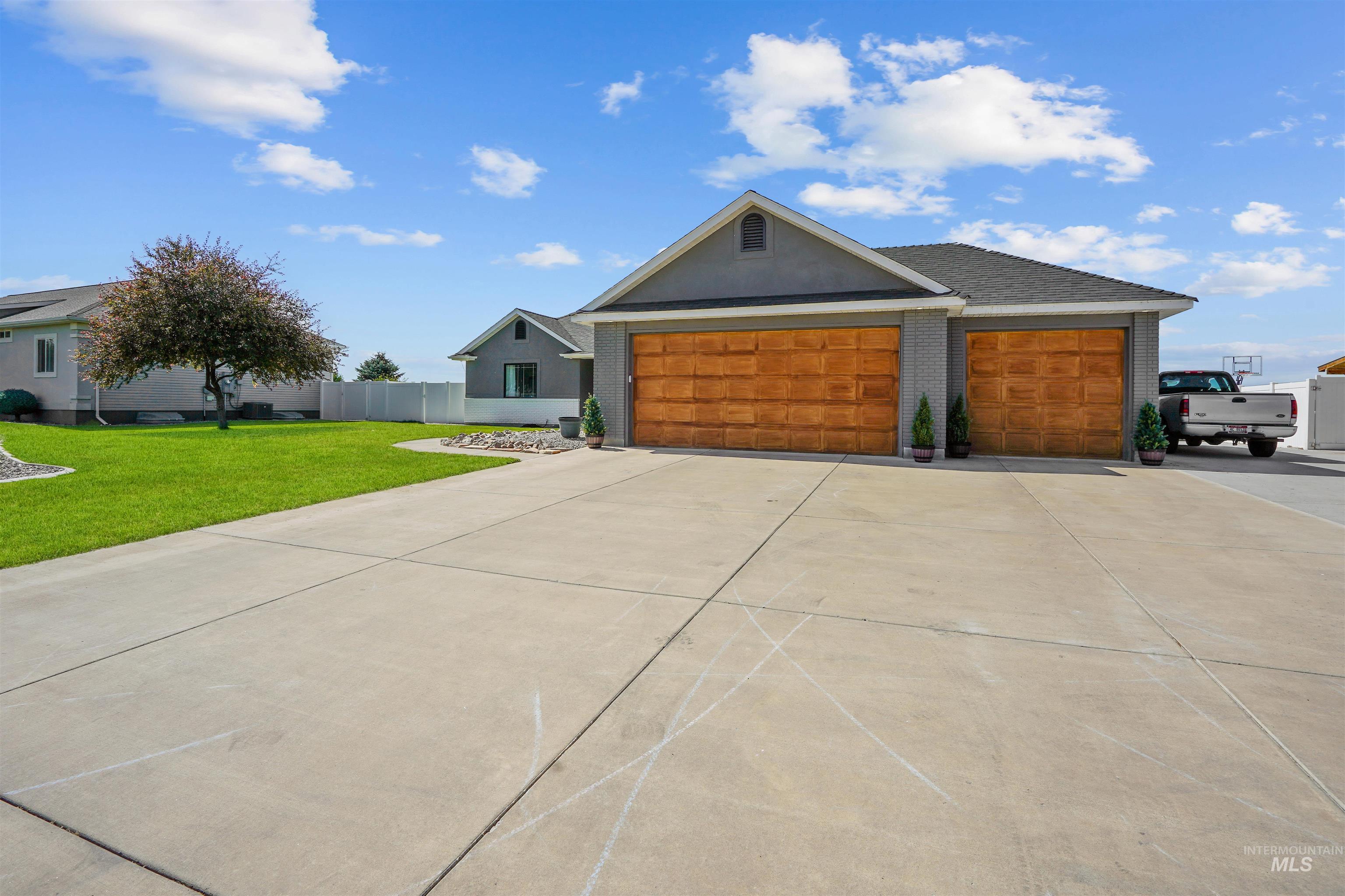 View of front facade featuring driveway, brick siding, and a garage