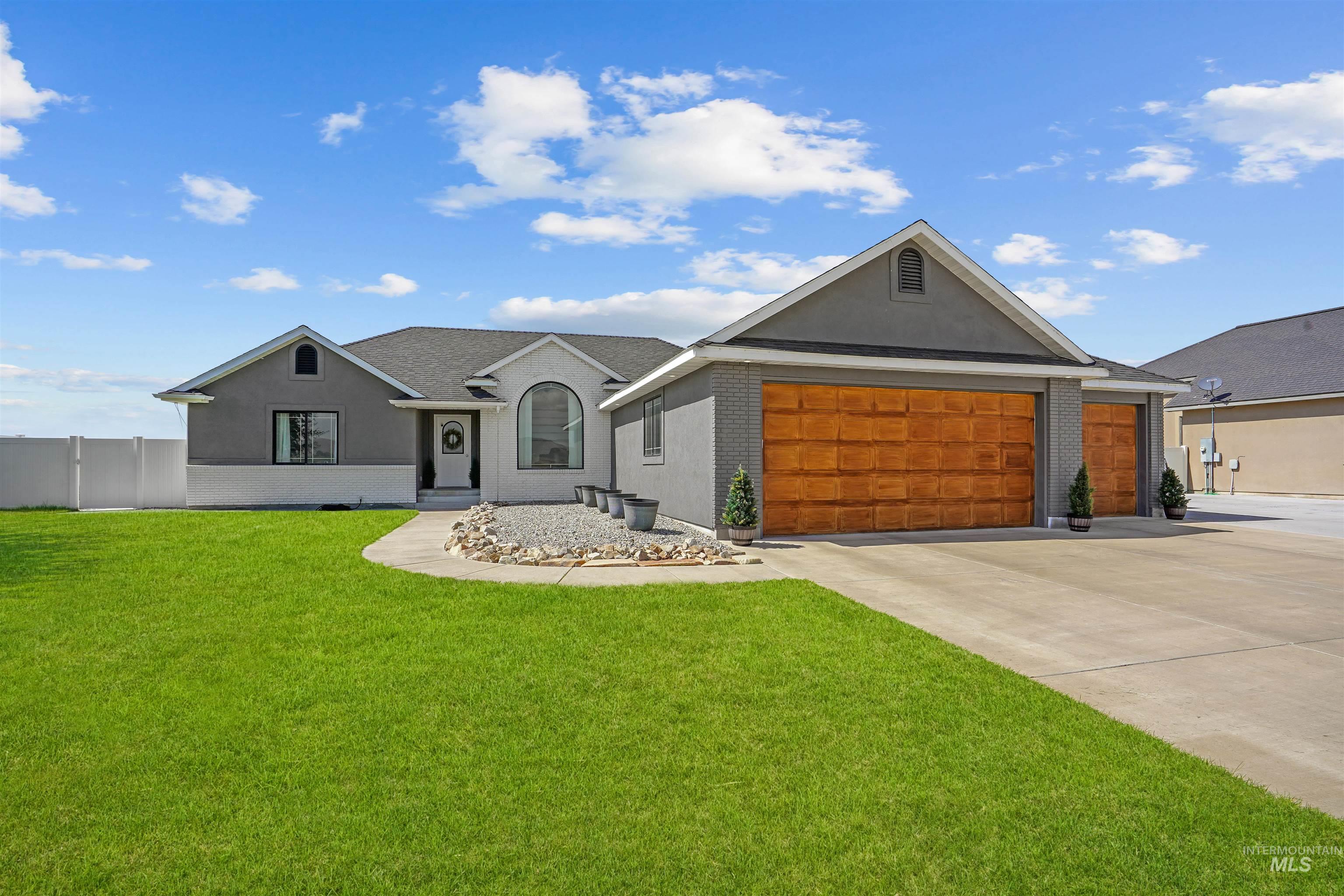 Ranch-style home featuring driveway, stucco siding, a garage, and brick siding
