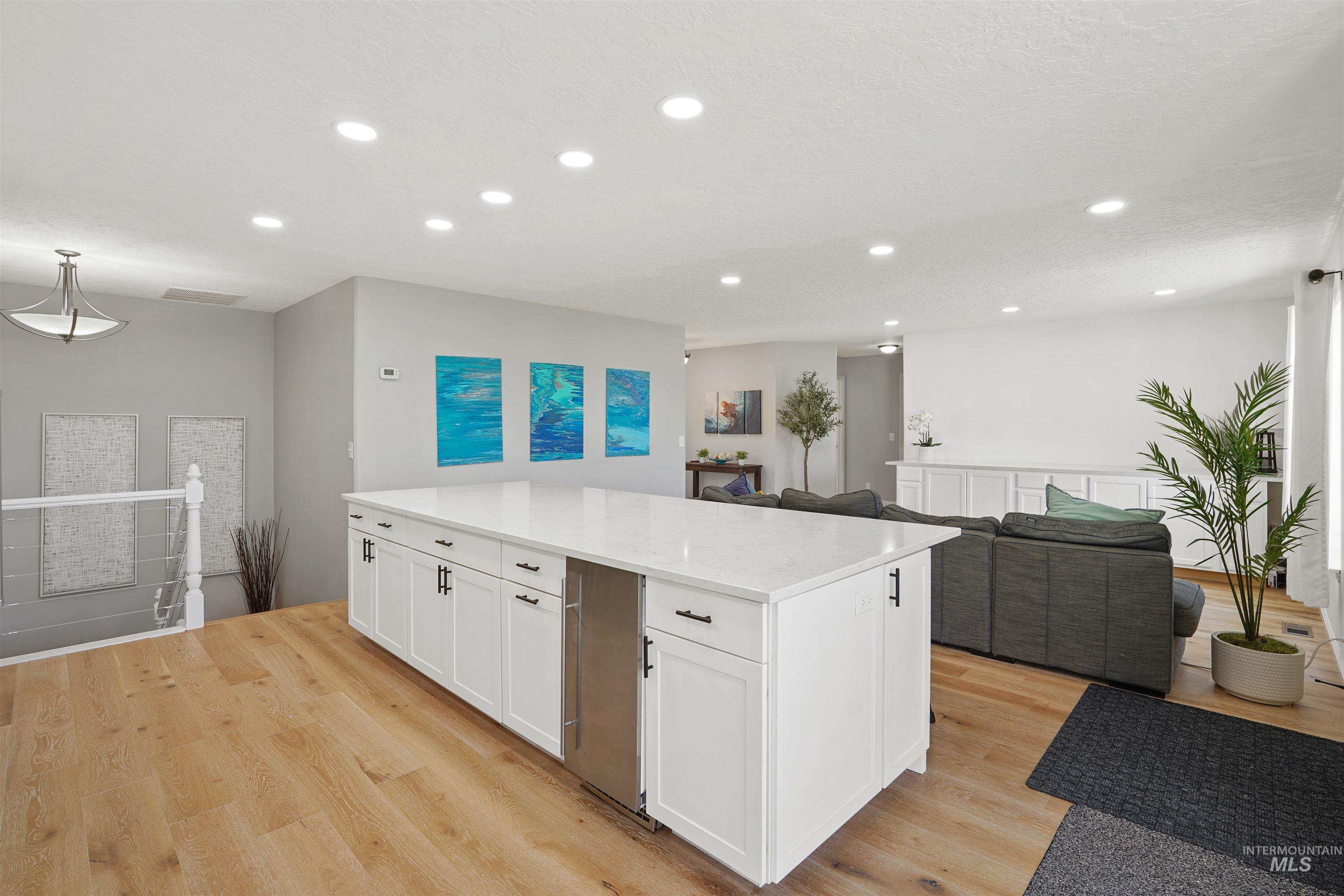 Kitchen featuring open floor plan, recessed lighting, white cabinets, a center island, and light wood-style flooring
