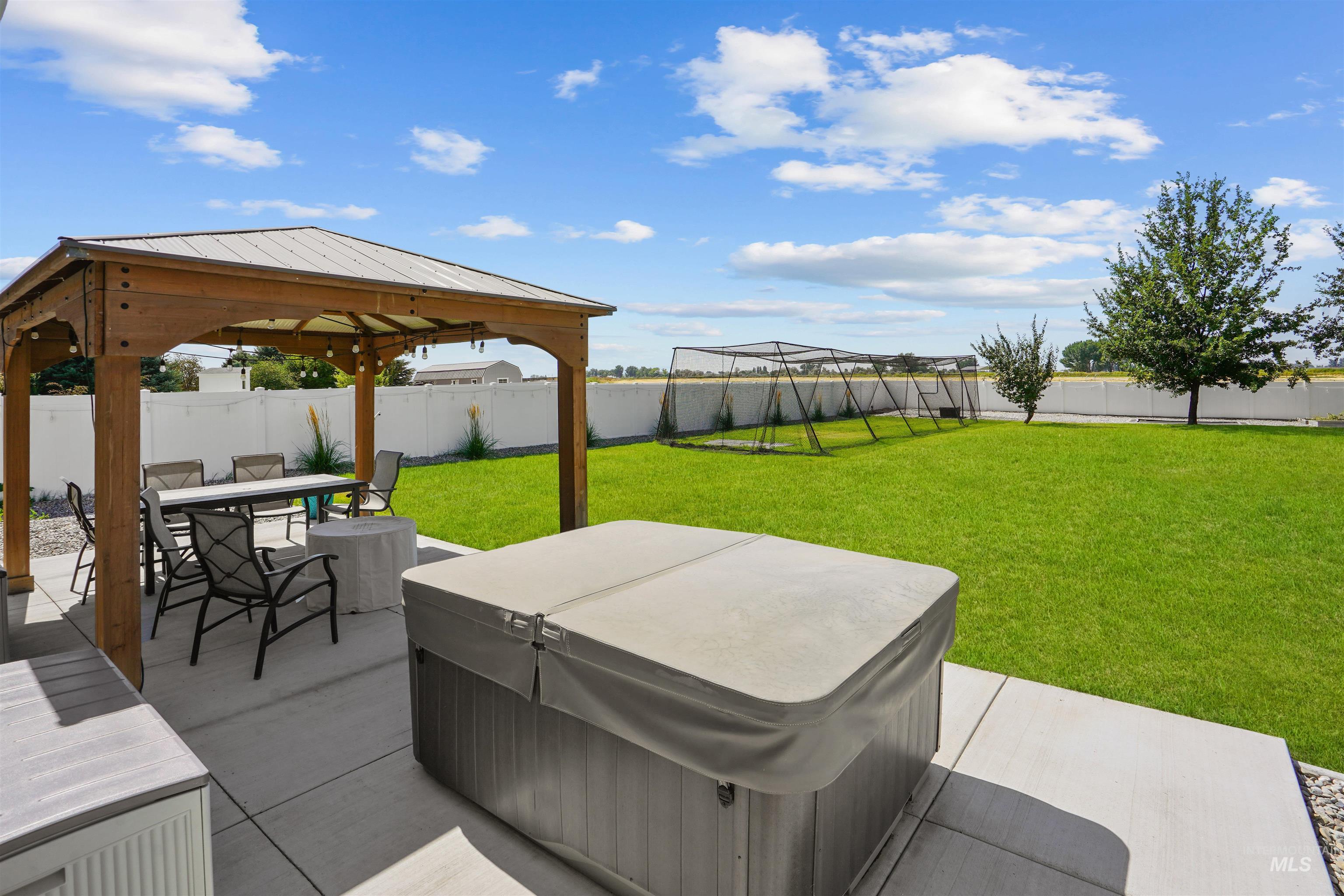 Fenced backyard with a patio area, a hot tub, a gazebo, and outdoor dining space